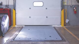 Loading dock entrance with mechanical pit leveler