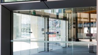 Modern glass pedestrian door at an office building entrance with automatic access system