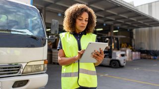 Woman supervising the dispatch of trucks at a distribution warehouse 1472189909 min