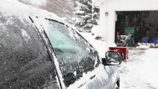 Car Covered In Snow Parked On A Snowy Driveway With Garage Door Opened
