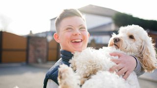 Child Holding Dog In Driveway Min