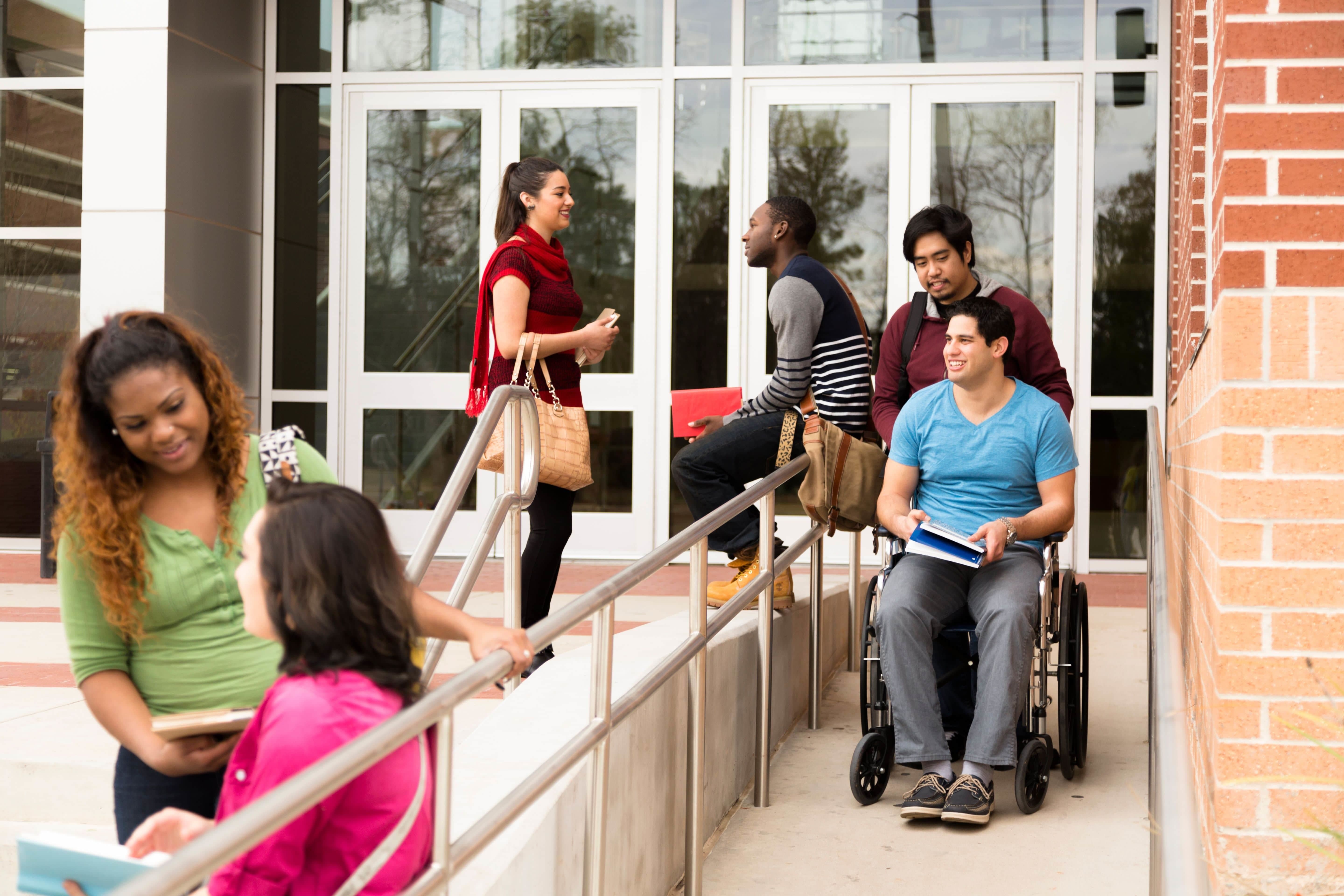 busy campus entrance with ramp for student using wheelchair