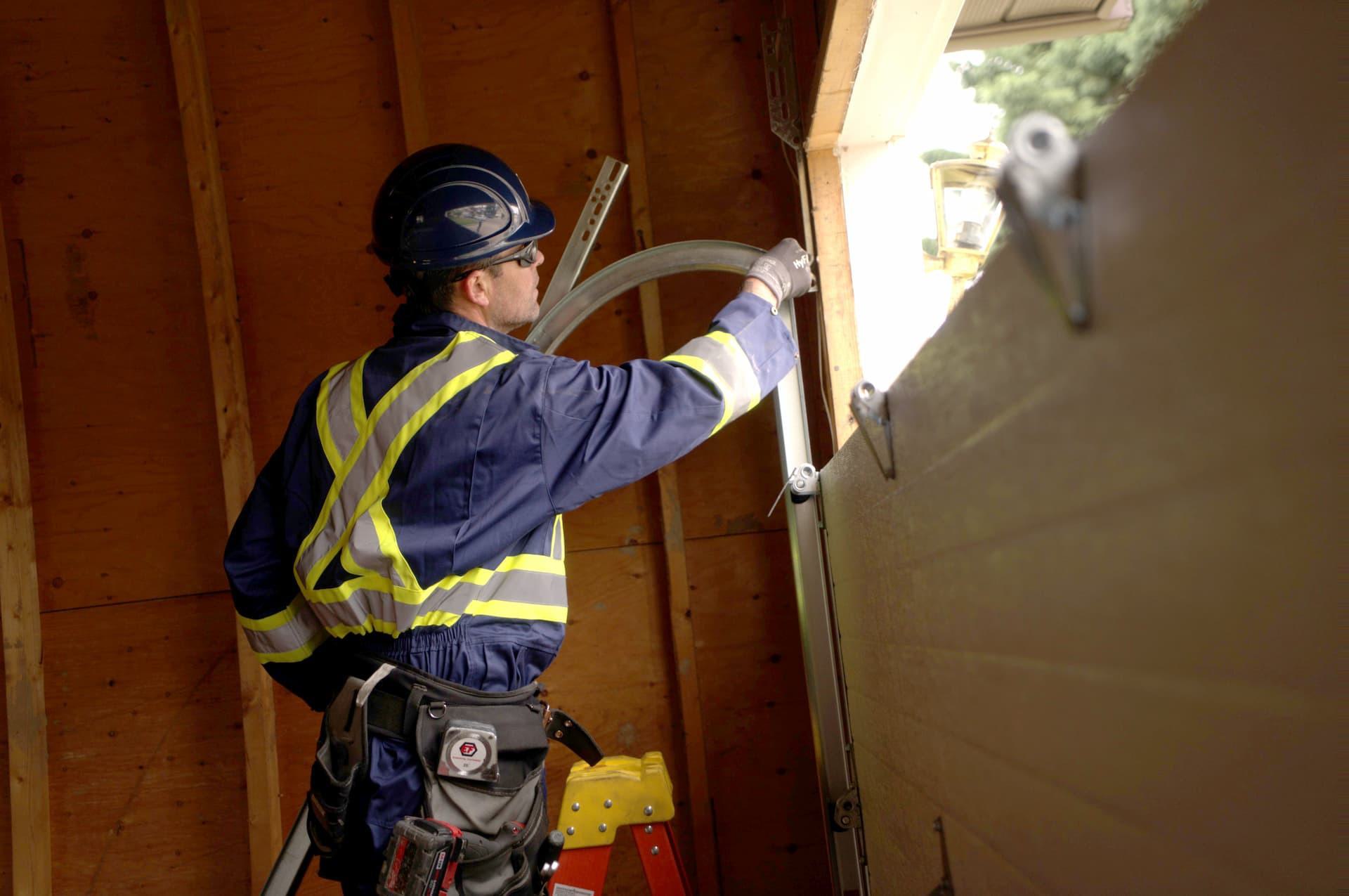 Creative Door Services technician installing garage door track