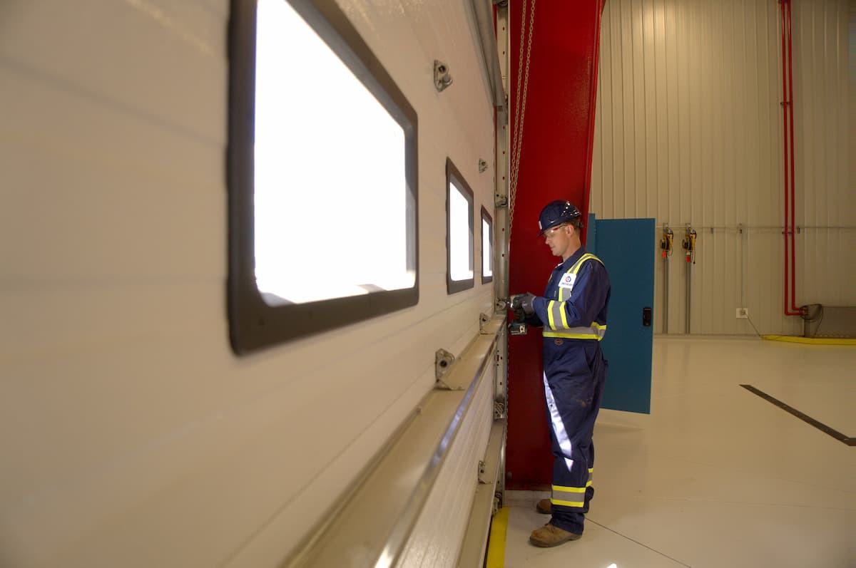 Creative Door Services technician maintaining commercial sectional door rollers and tracks
