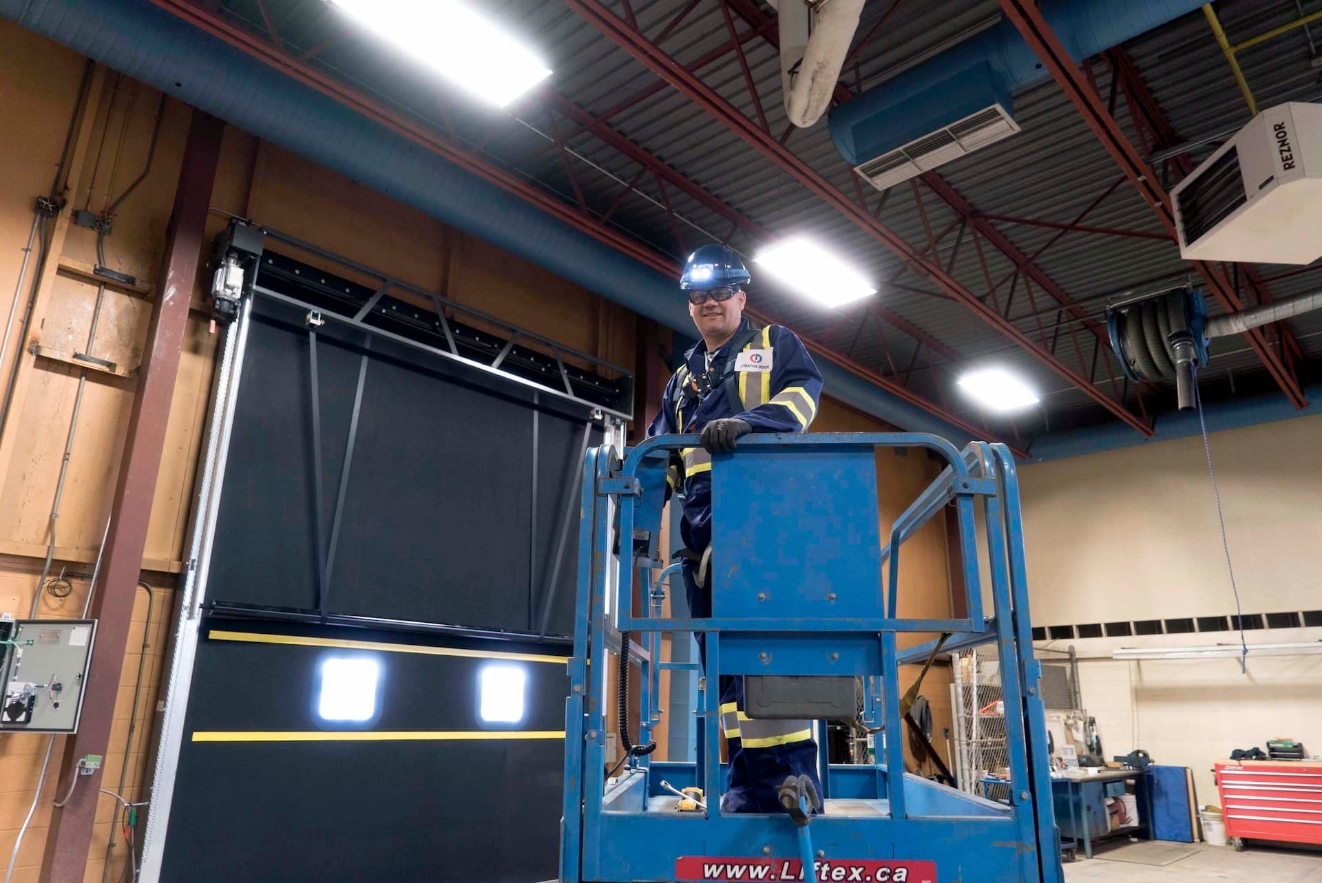 Creative Door Services technician on lift installing warehouse door