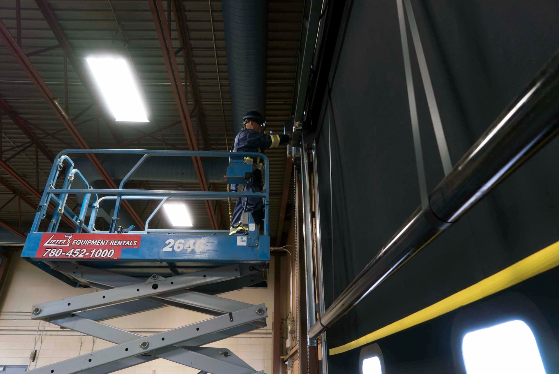 Creative Door Services technician on lift performing commercial door maintenance