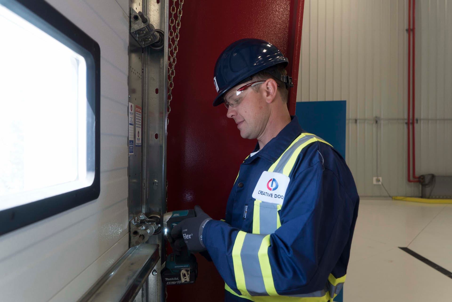 Creative Door Services technician repairing commercial sectional door tracks and rollers
