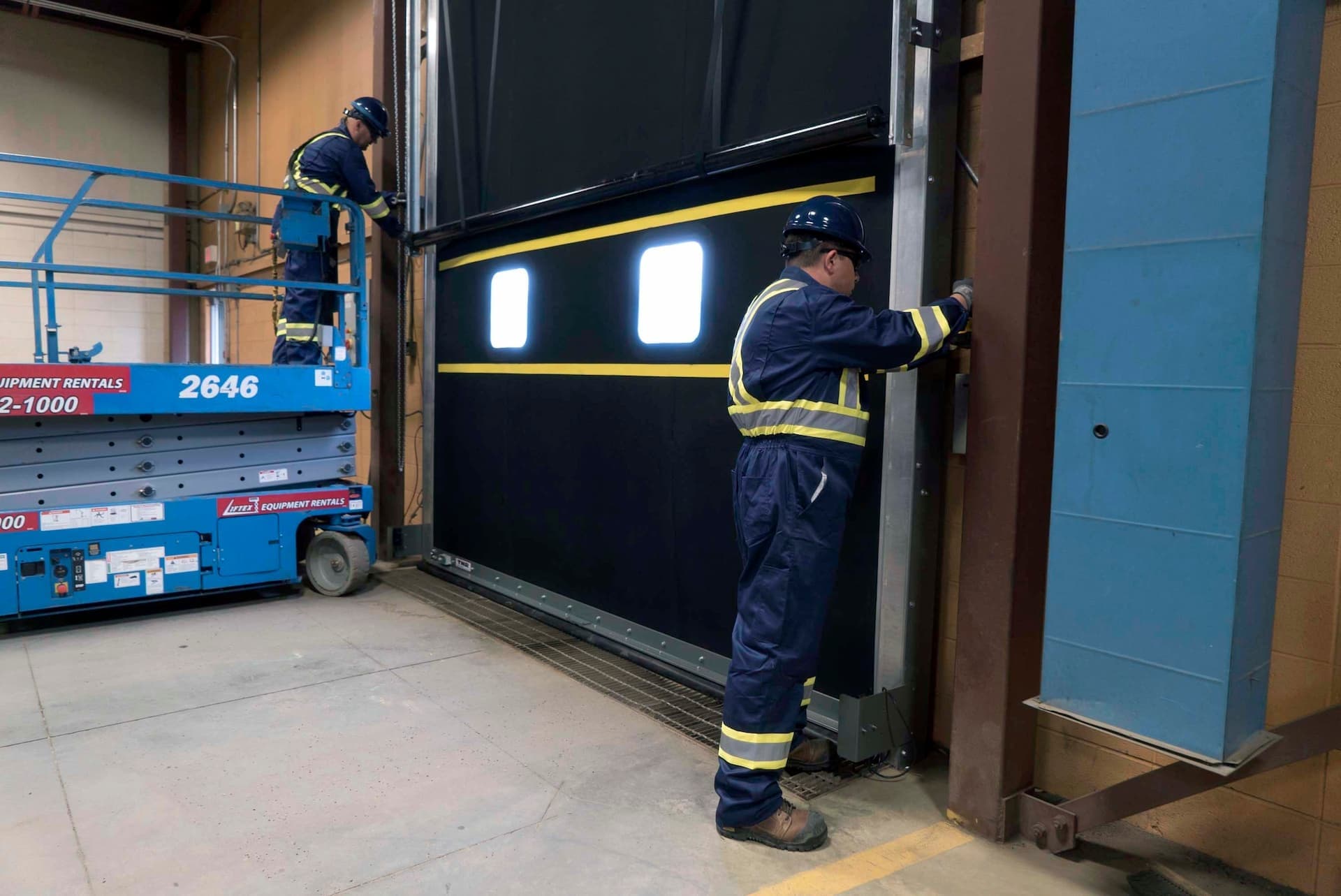 Creative Door Services technicians maintaining commercial door tracks
