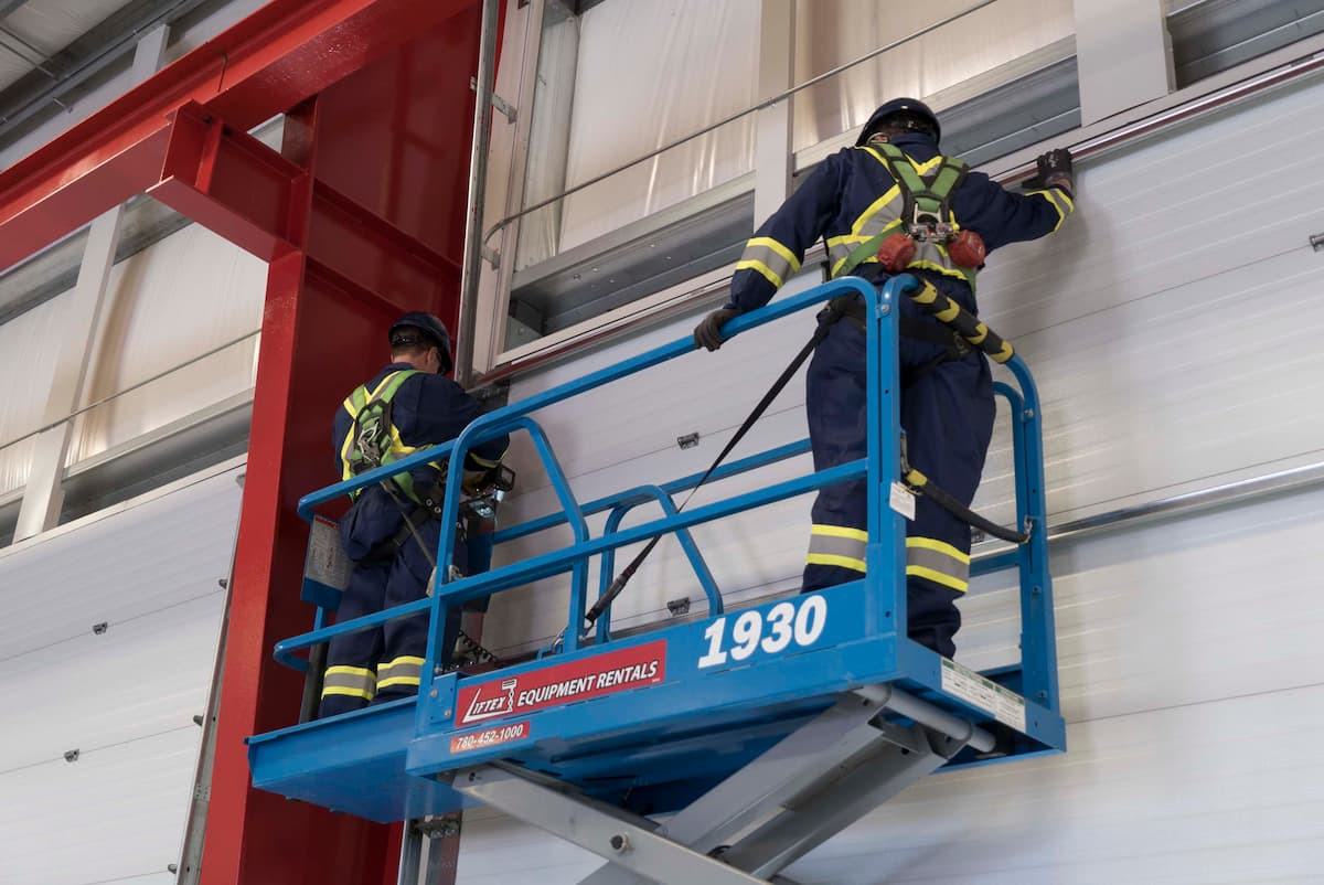 CDS technicians on forklift maintaining industrial sectional door tracks