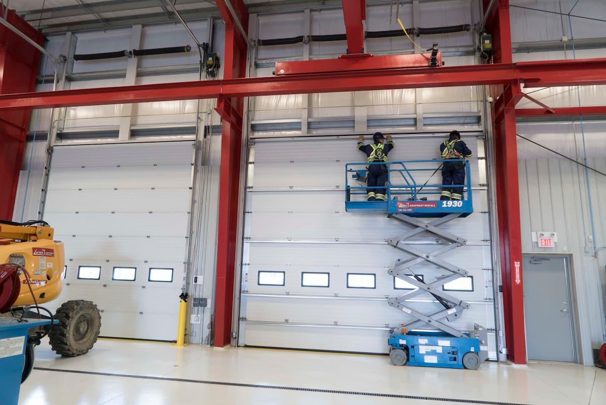 CDS technicians on forklift performing industrial sectional door maintenance