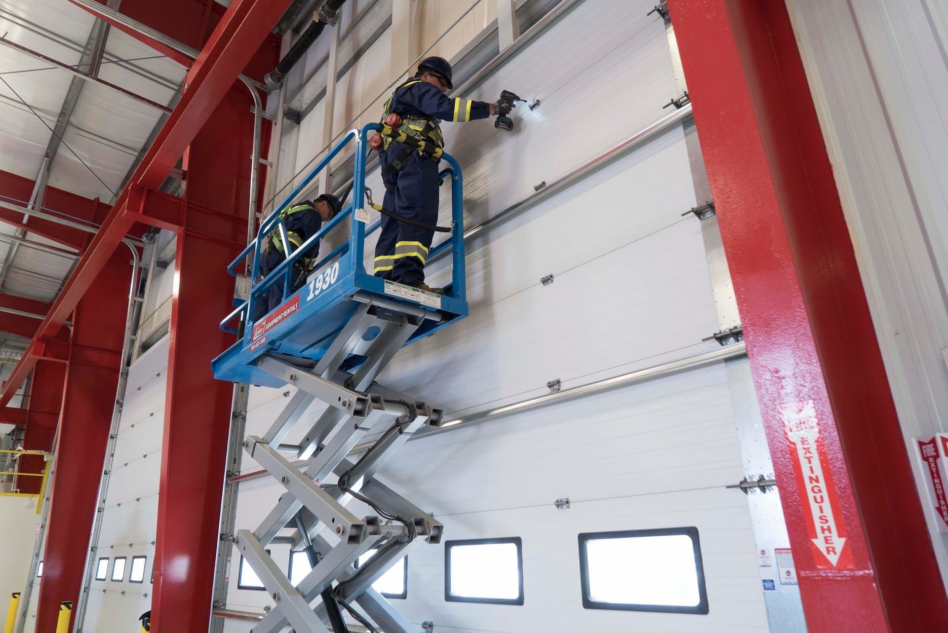 Creative Door Services technicians on forklift repairing commercial sectional door
