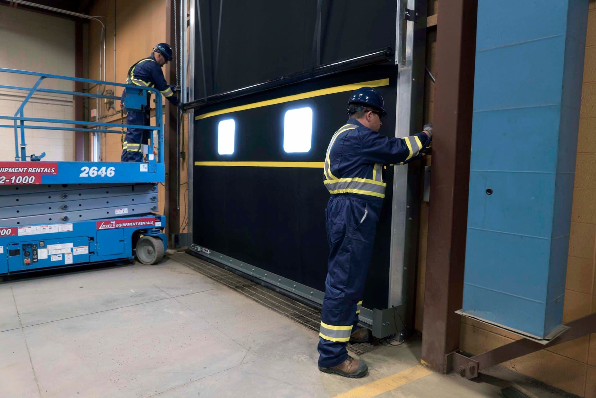 Creative Door Services technicians repairing commercial door tracks
