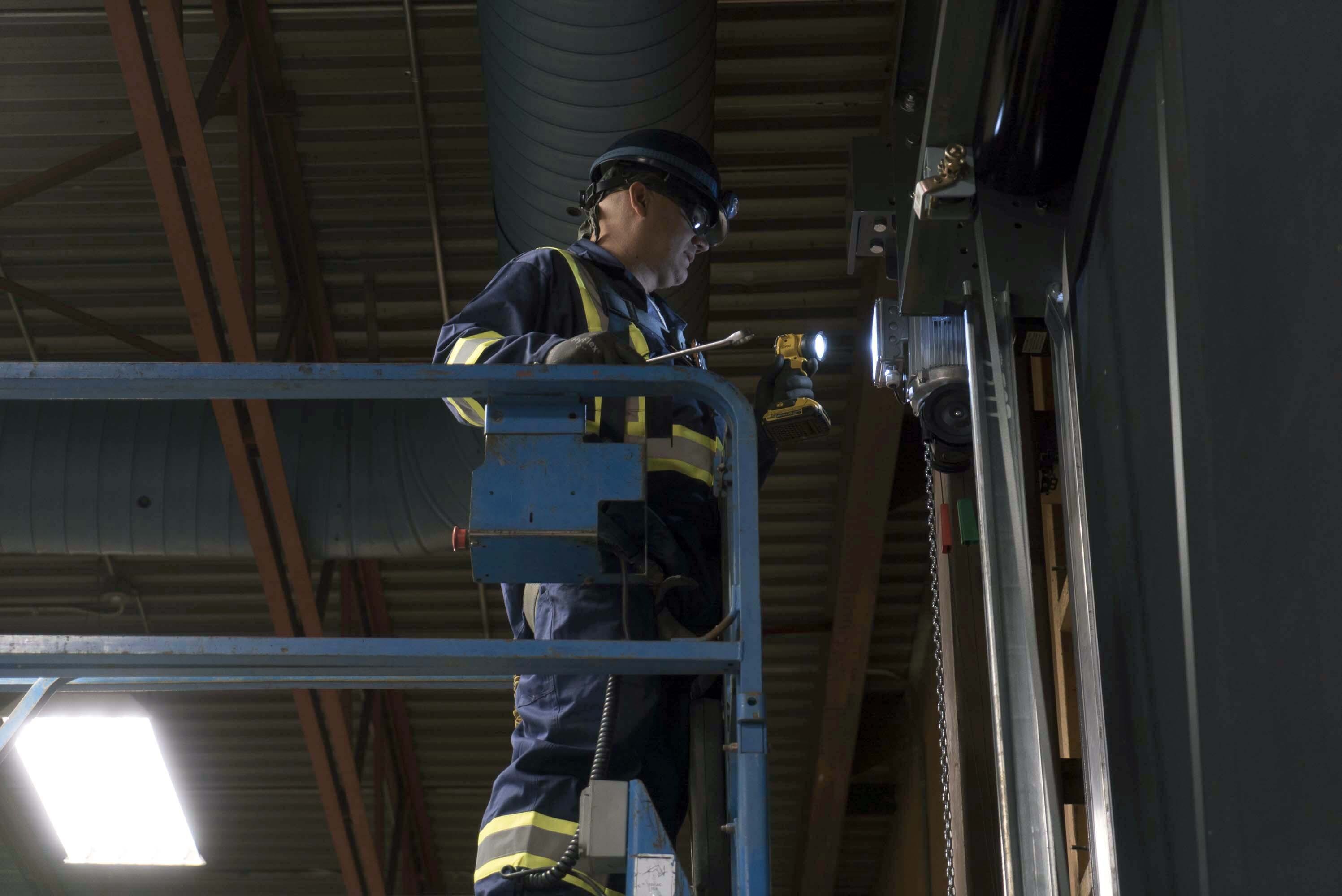 Creative Door Services technician on a forklift inspecting a commercial door