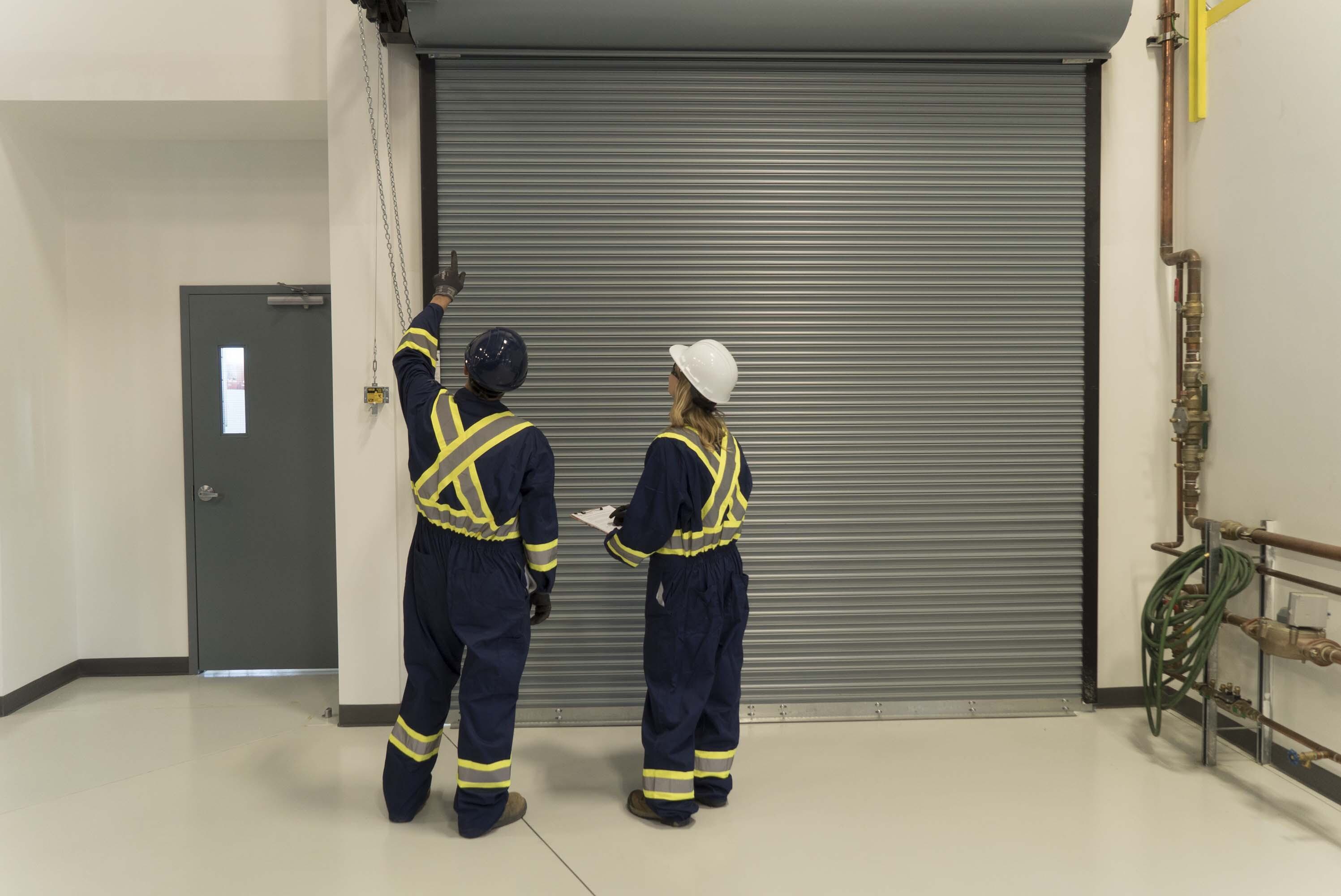Creative Door Services technicians inspecting a rolling door