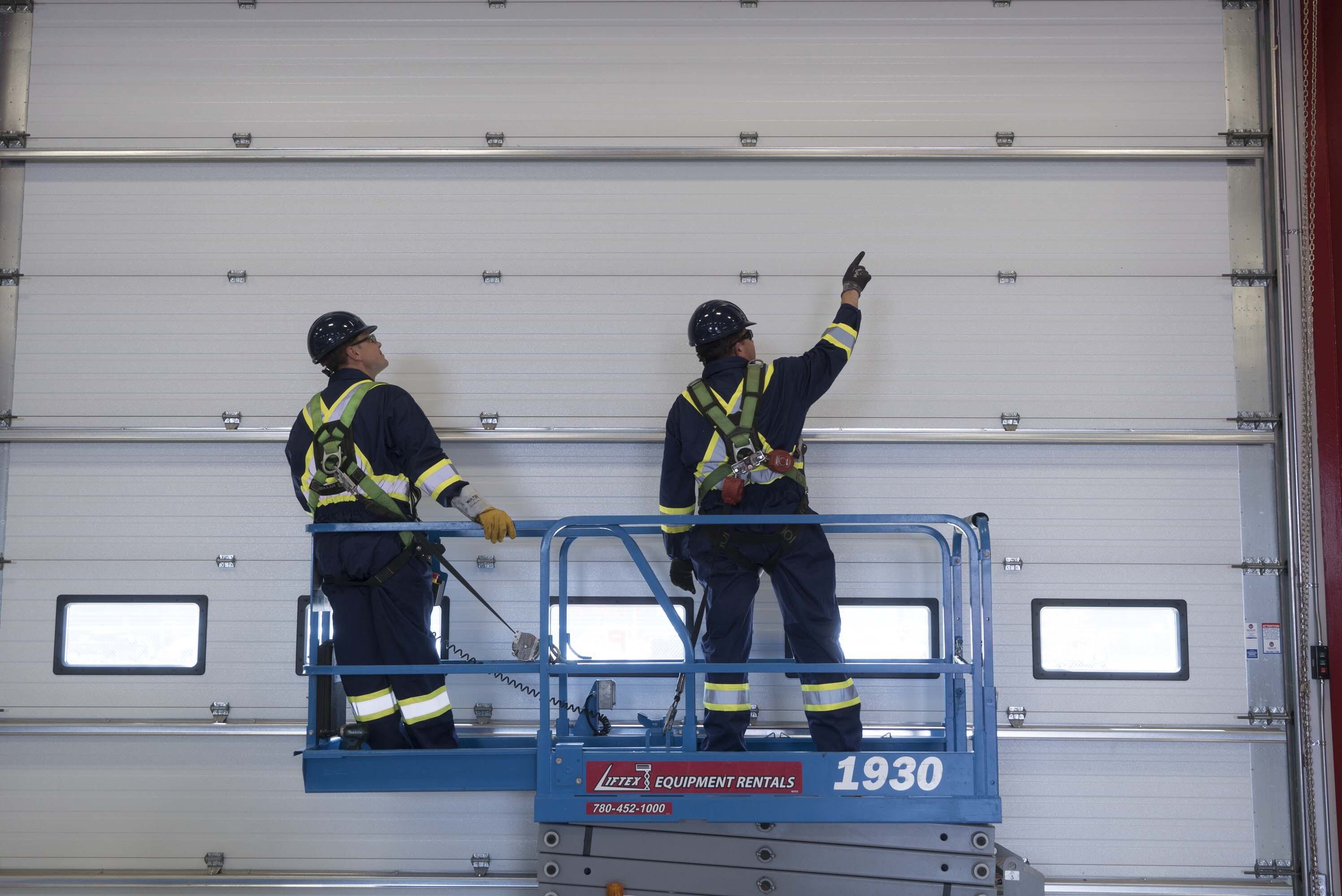 Creative Door Services technician on a forklift inspecting a commercial sectional door