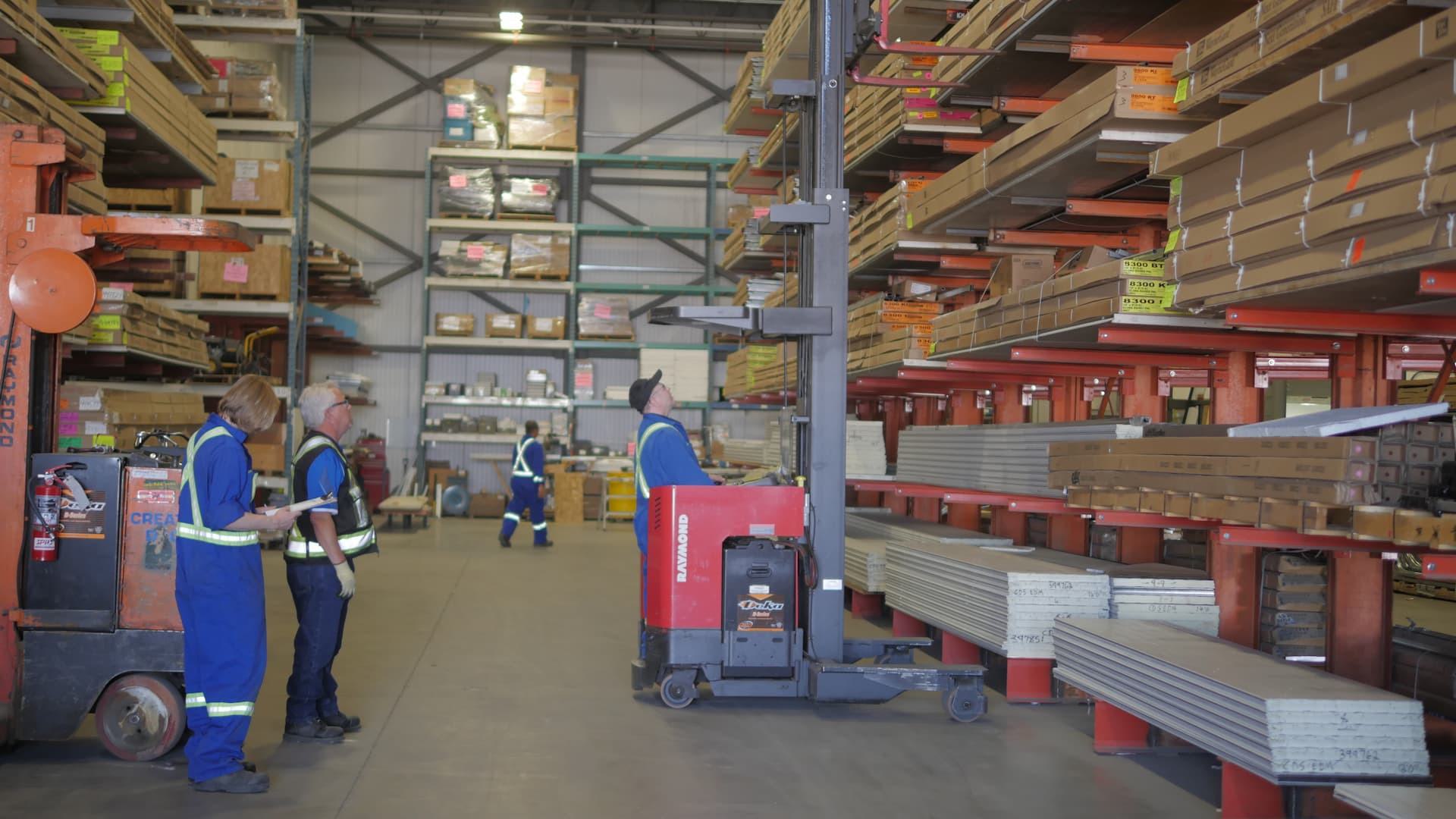 Creative Door Services warehouse team organizing and handling inventory with forklifts and shelving racks