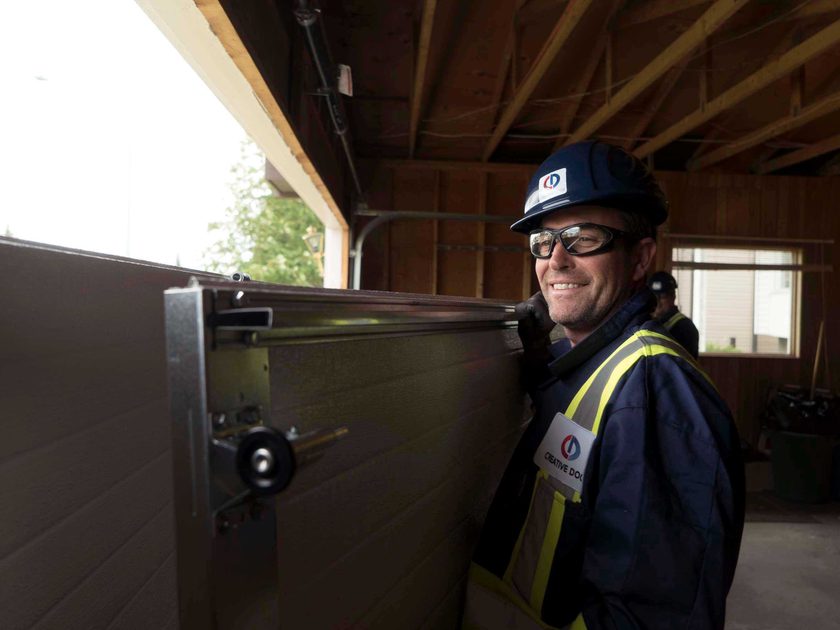 Creative Door Services technician installing garage door panel