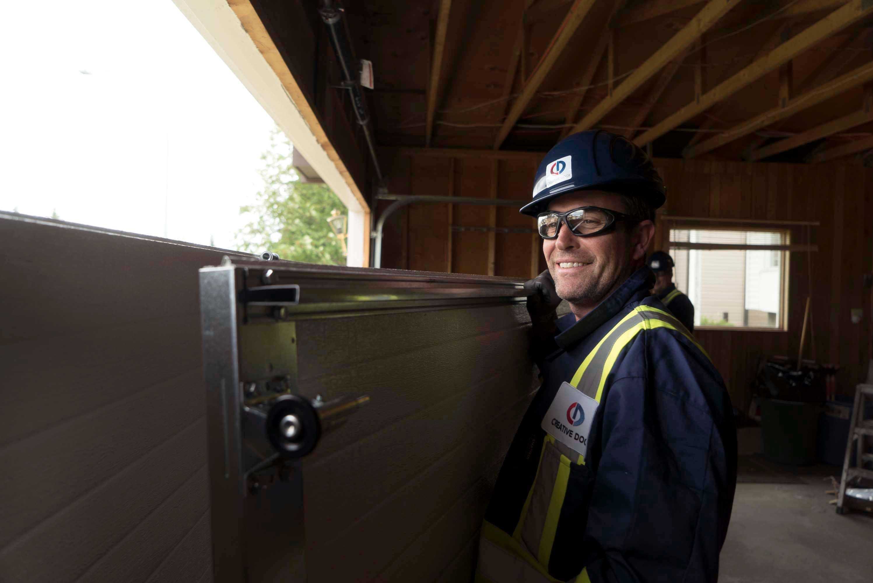 smiling creative door technician installing or repairing a garage door