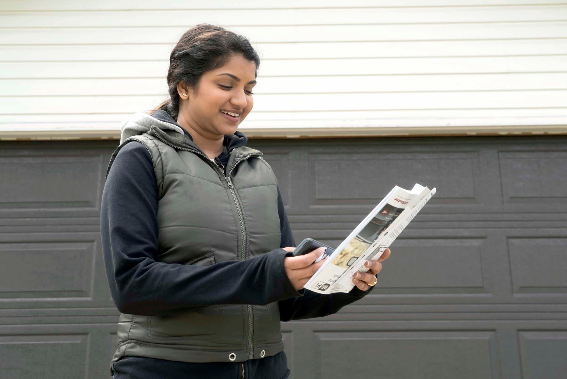 Customer reviewing sales brochure outside her home near a garage door