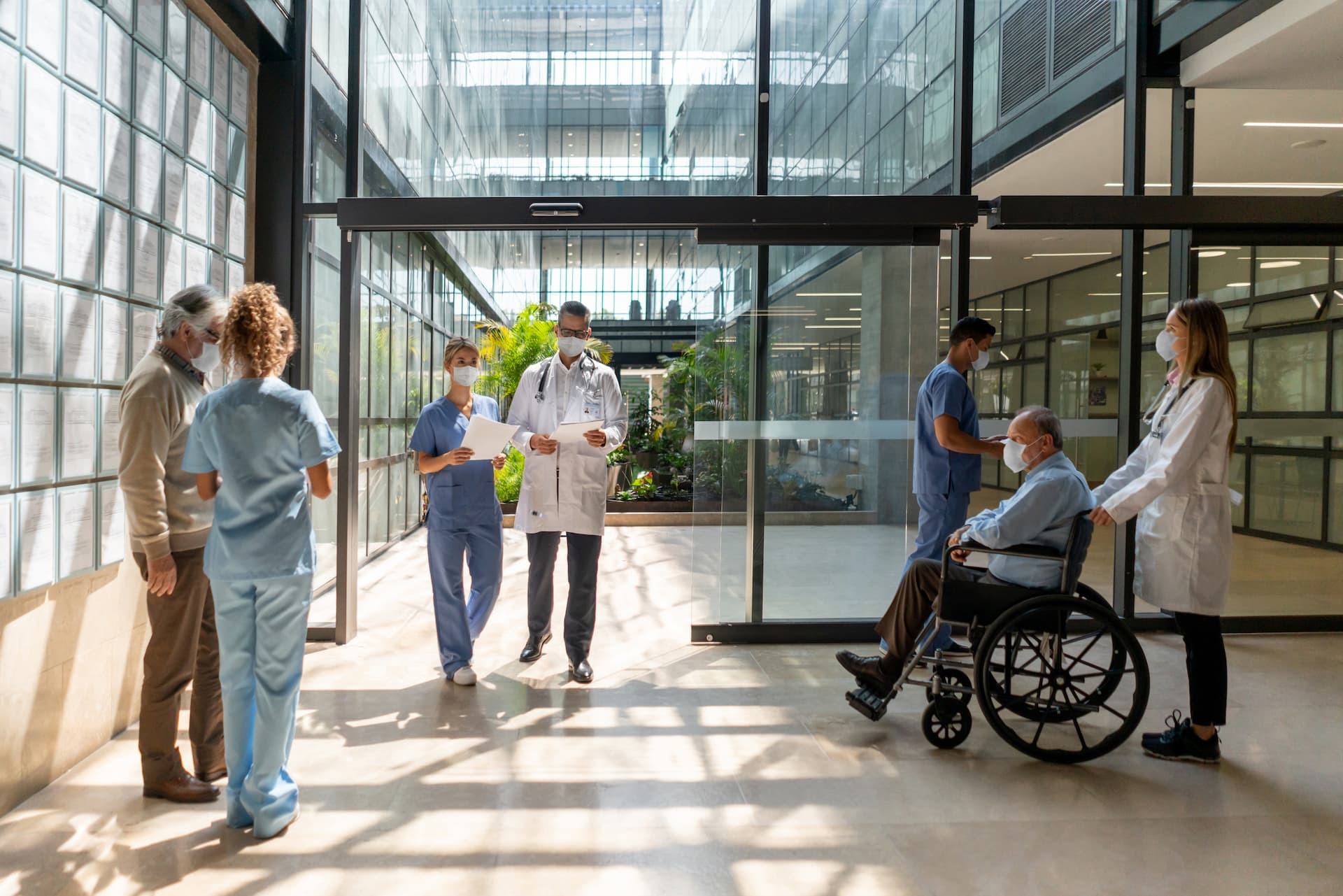 Medical staff and patients using an automatic glass entrance in a modern healthcare facility