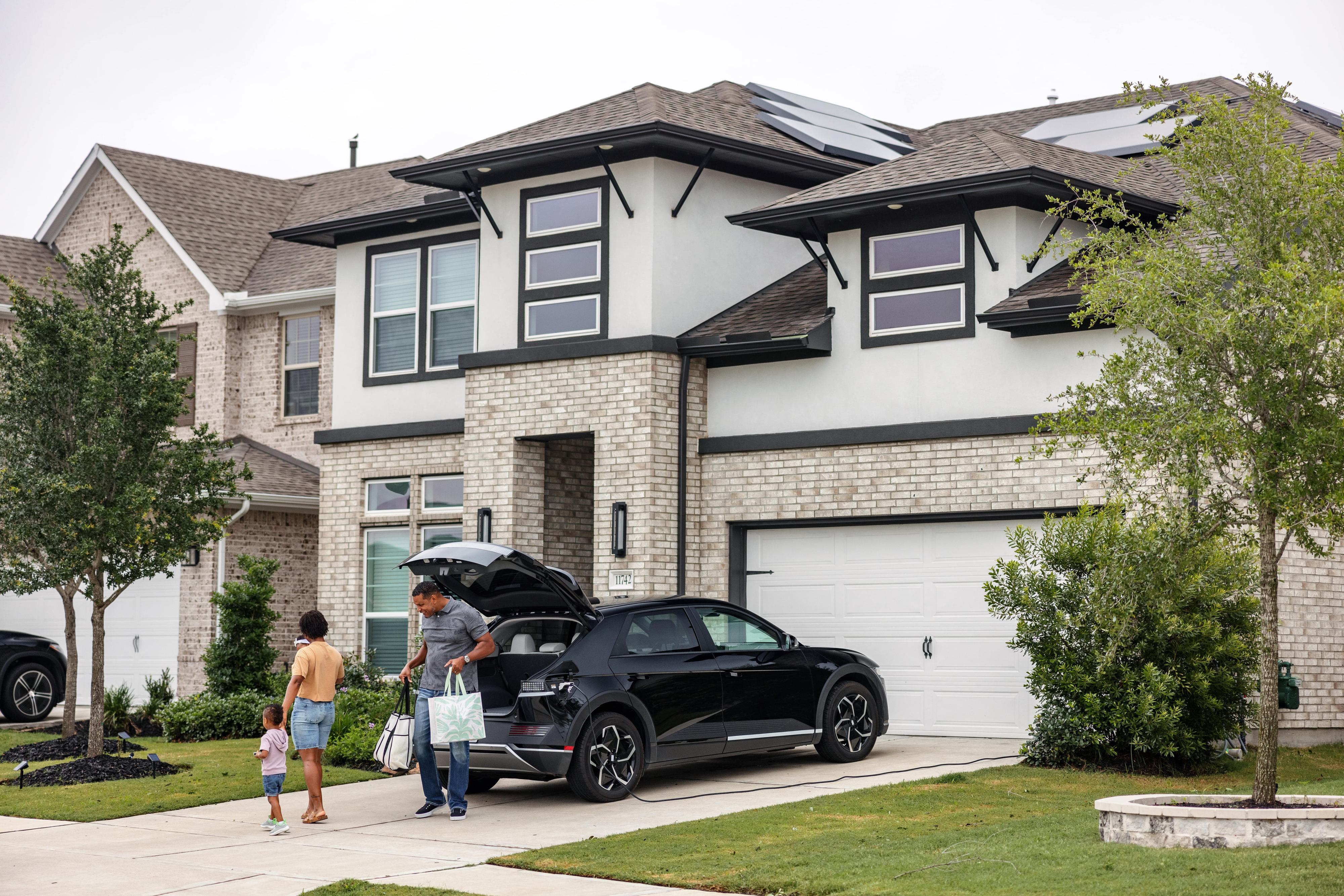 Family returning home with car parked in front of garage door
