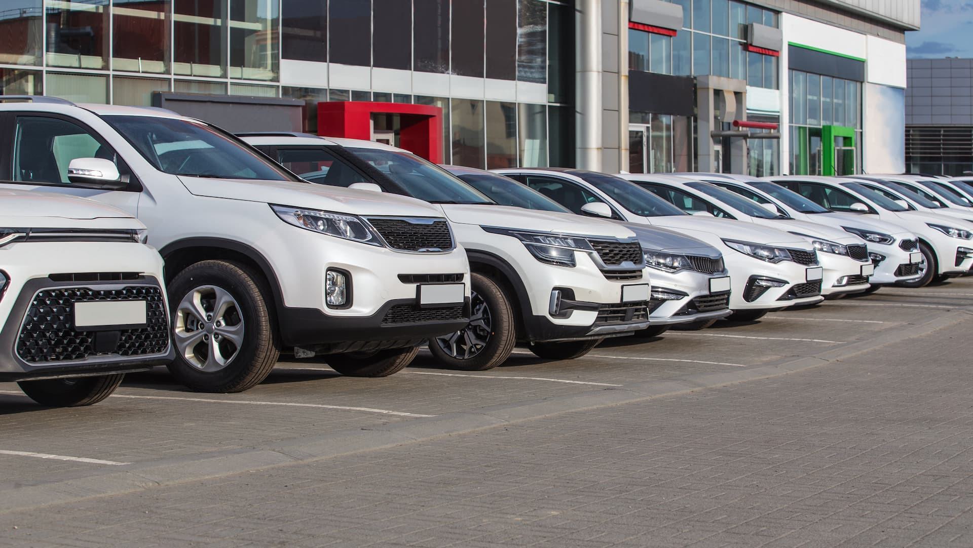 Row of vehicles parked outside an automotive dealership showcasing a modern showroom exterior