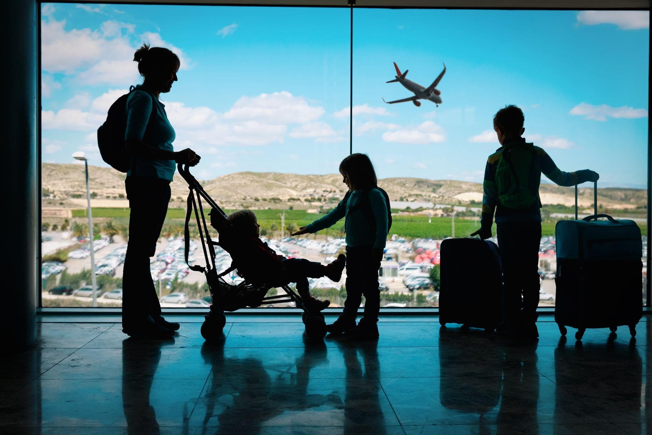 view of family waiting in airport with plane taking off in background