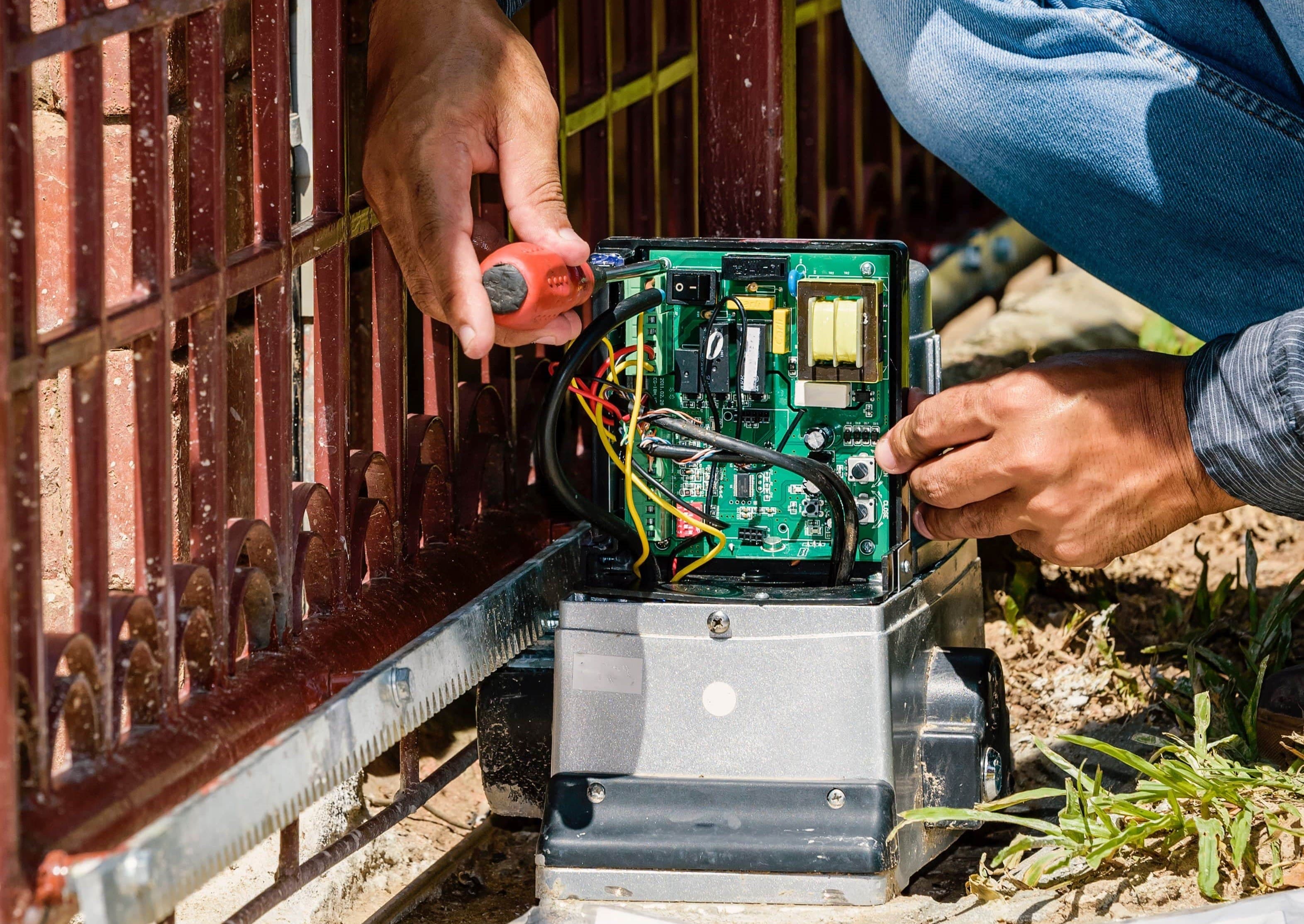 automatic gate technician working on wiring of operator