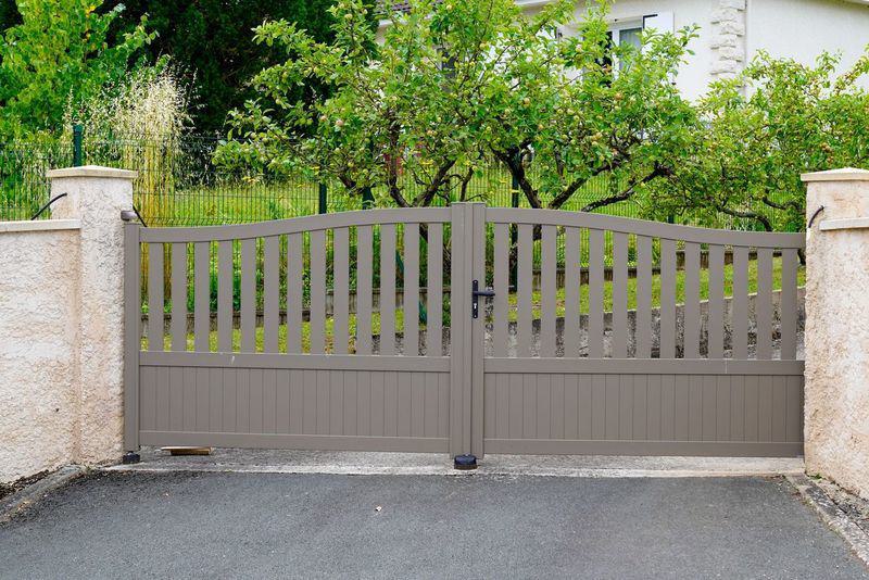 modern brown swing gate with garden in background