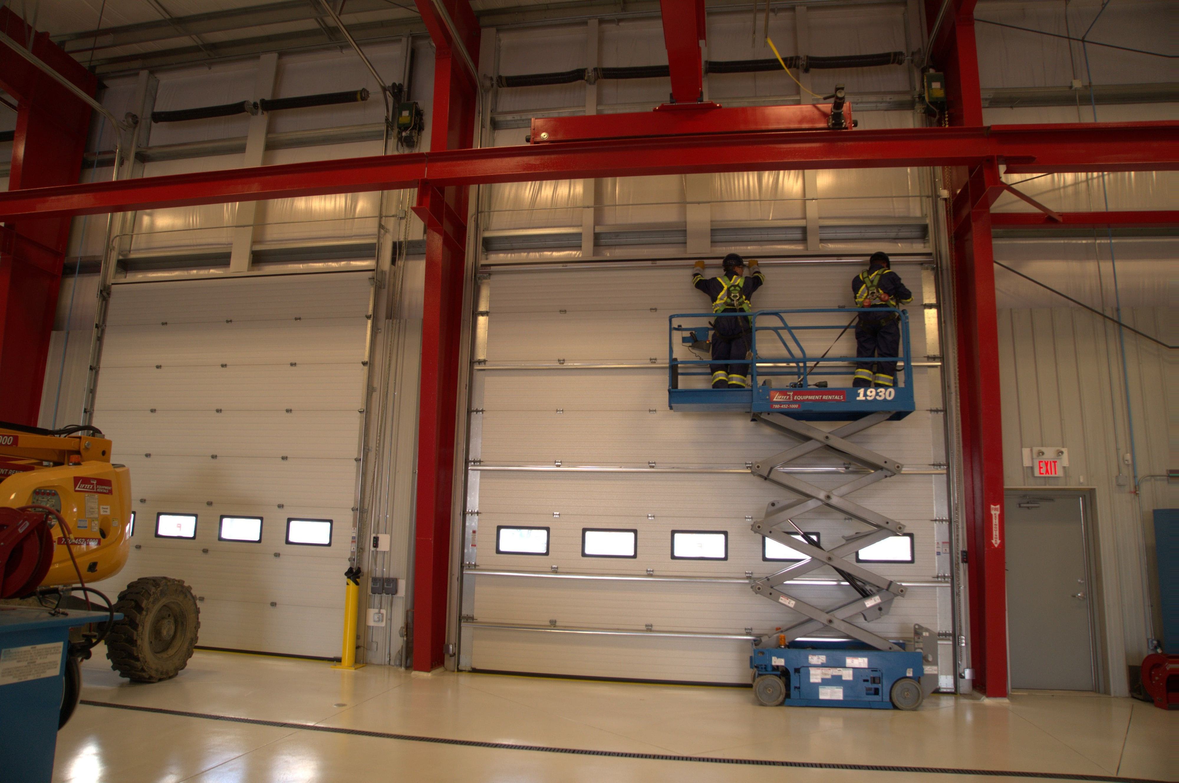 Creative Door Service technicians installing a new sectional door in a large warehouse