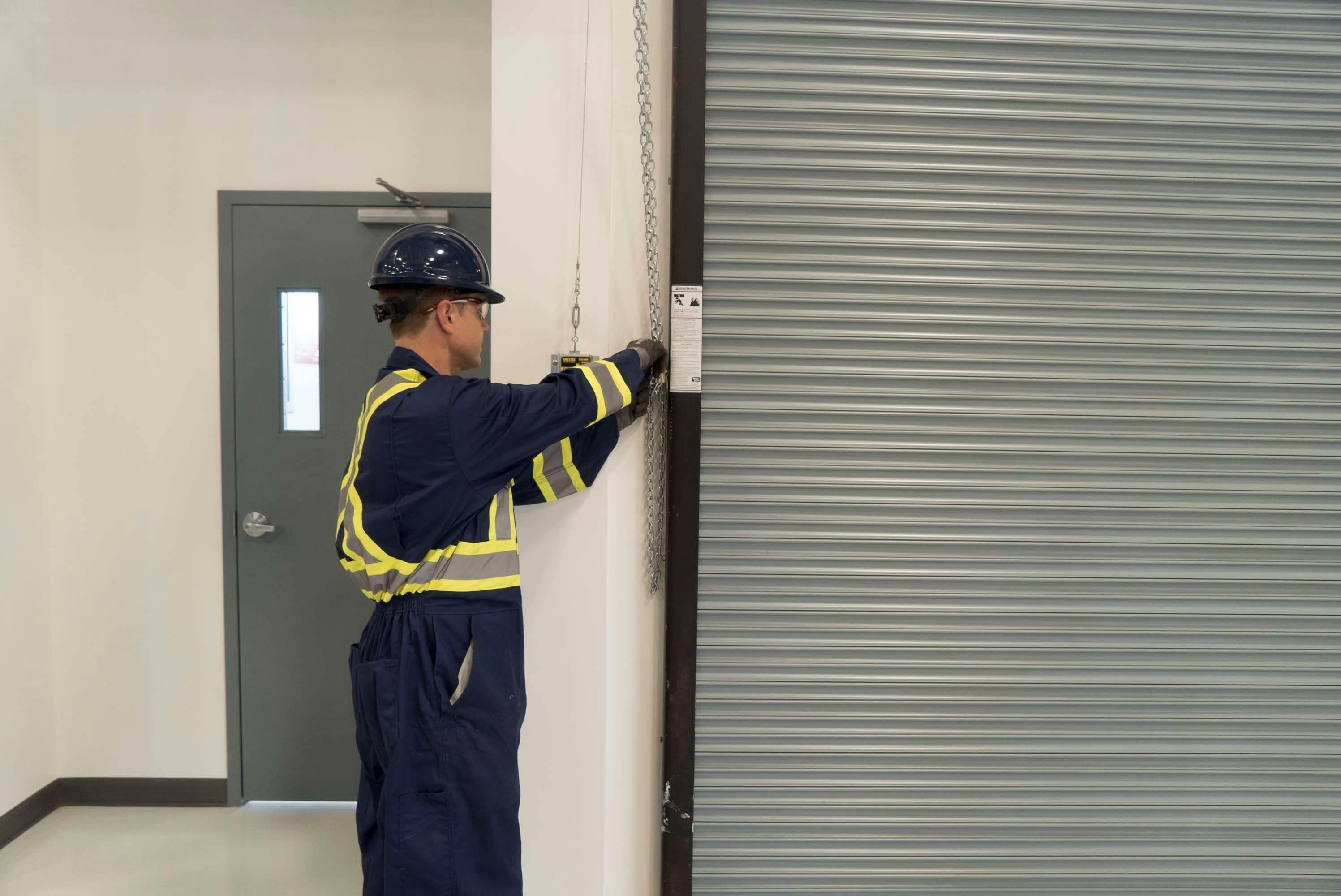 a CDS technician performing maintenance on a steel roll up sheet door