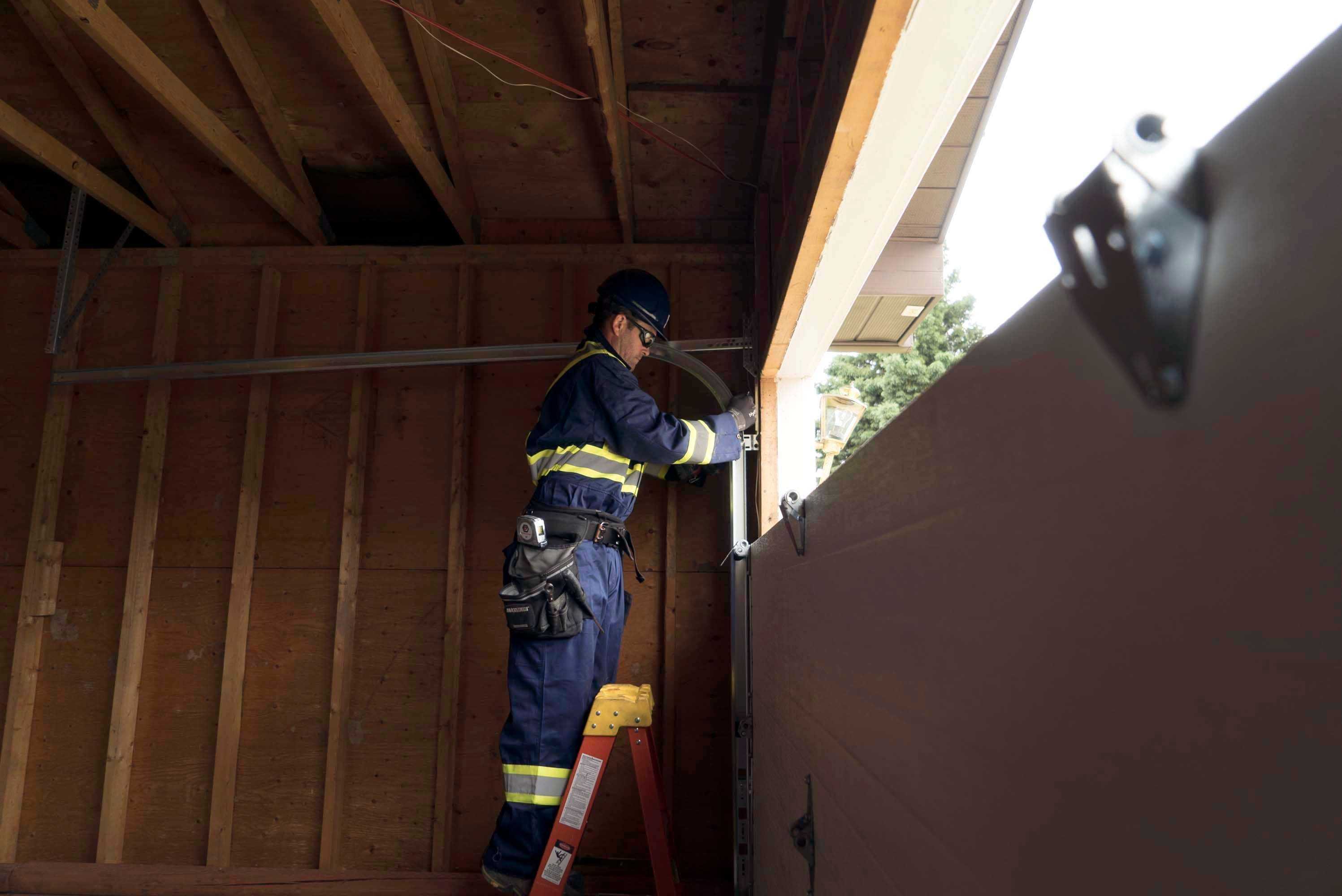 A technician from Creative Door inspecting track for garage door rollers A technician from Creative Door inspecting track for garage door rollers