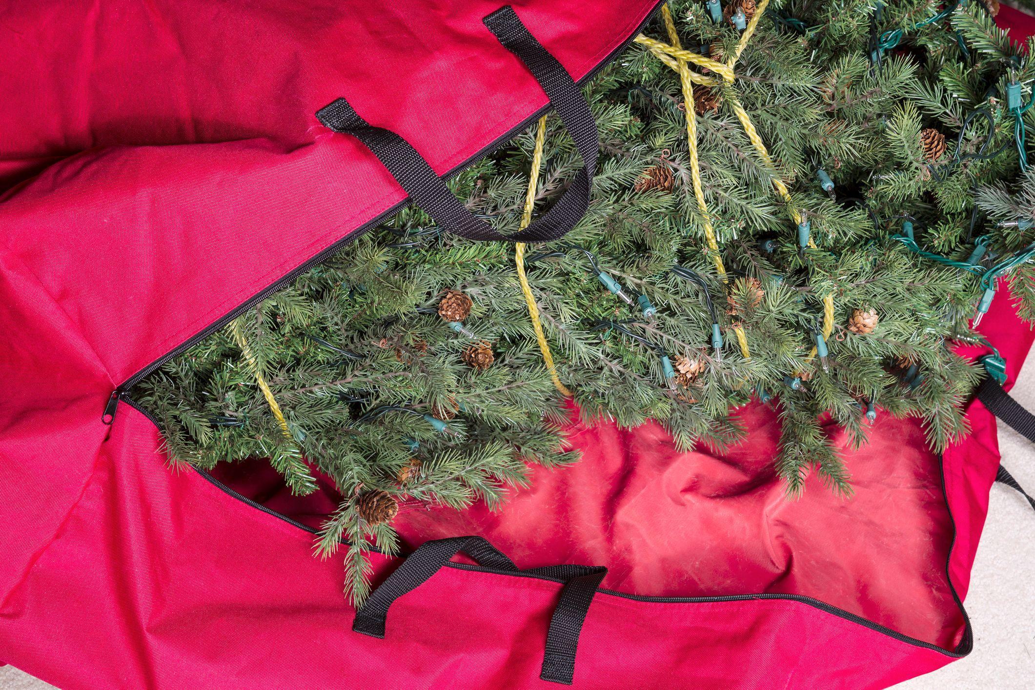 placing christmas tree in a big red storage bag placing christmas tree in a big red storage bag