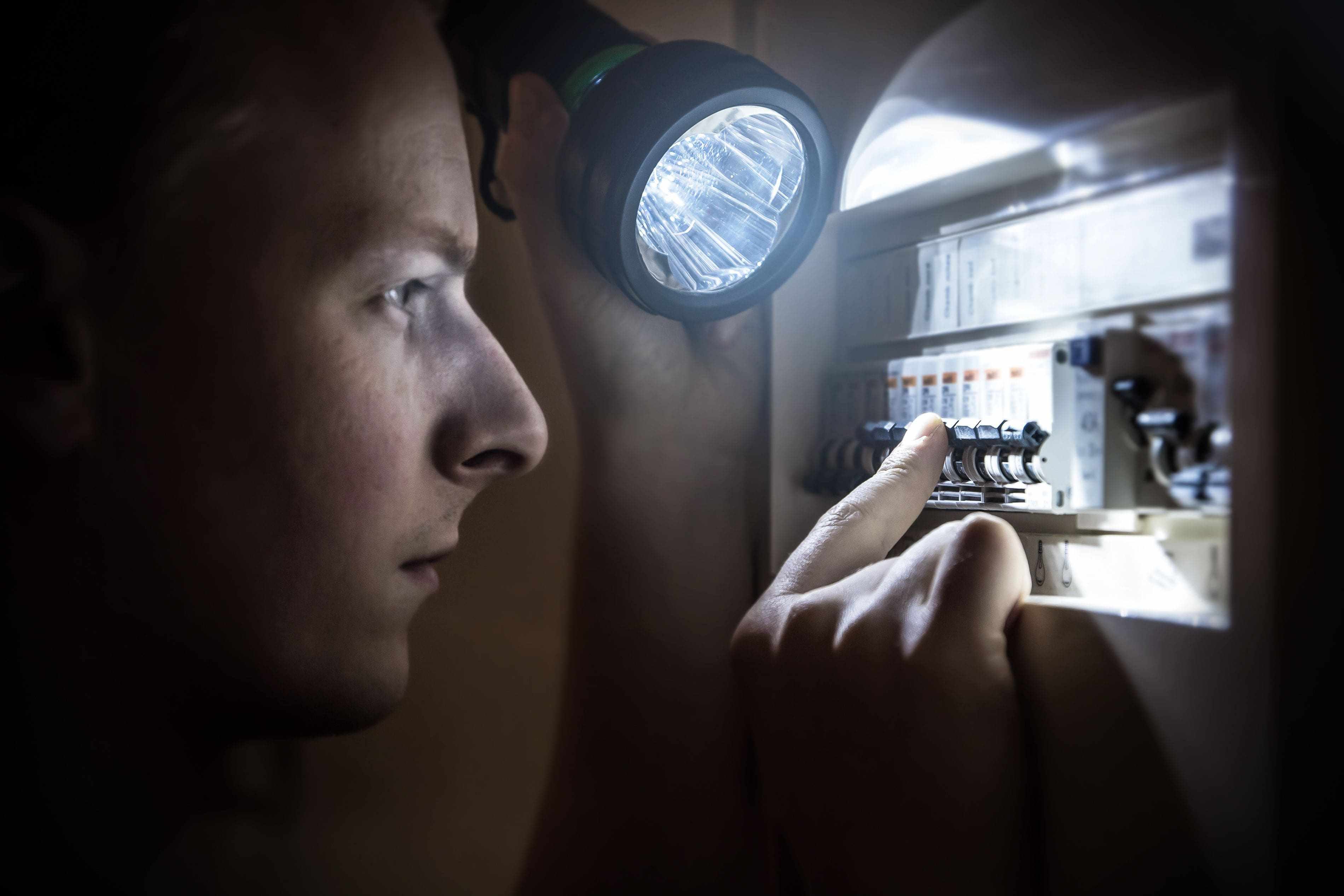 using flashlight to troubleshoot circuit breaker during power outage