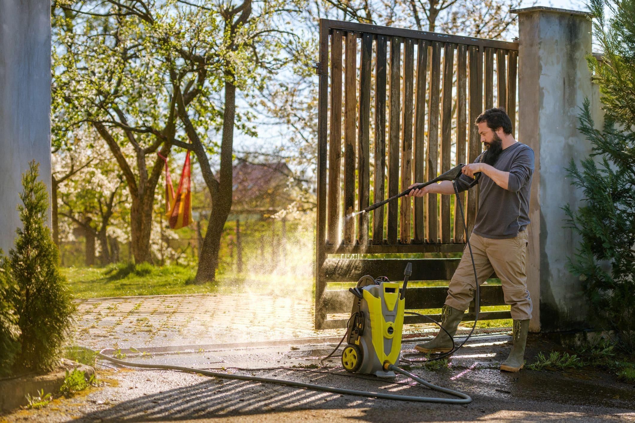 man cleaning swing gate area with powerwasher man cleaning swing gate area with powerwasher