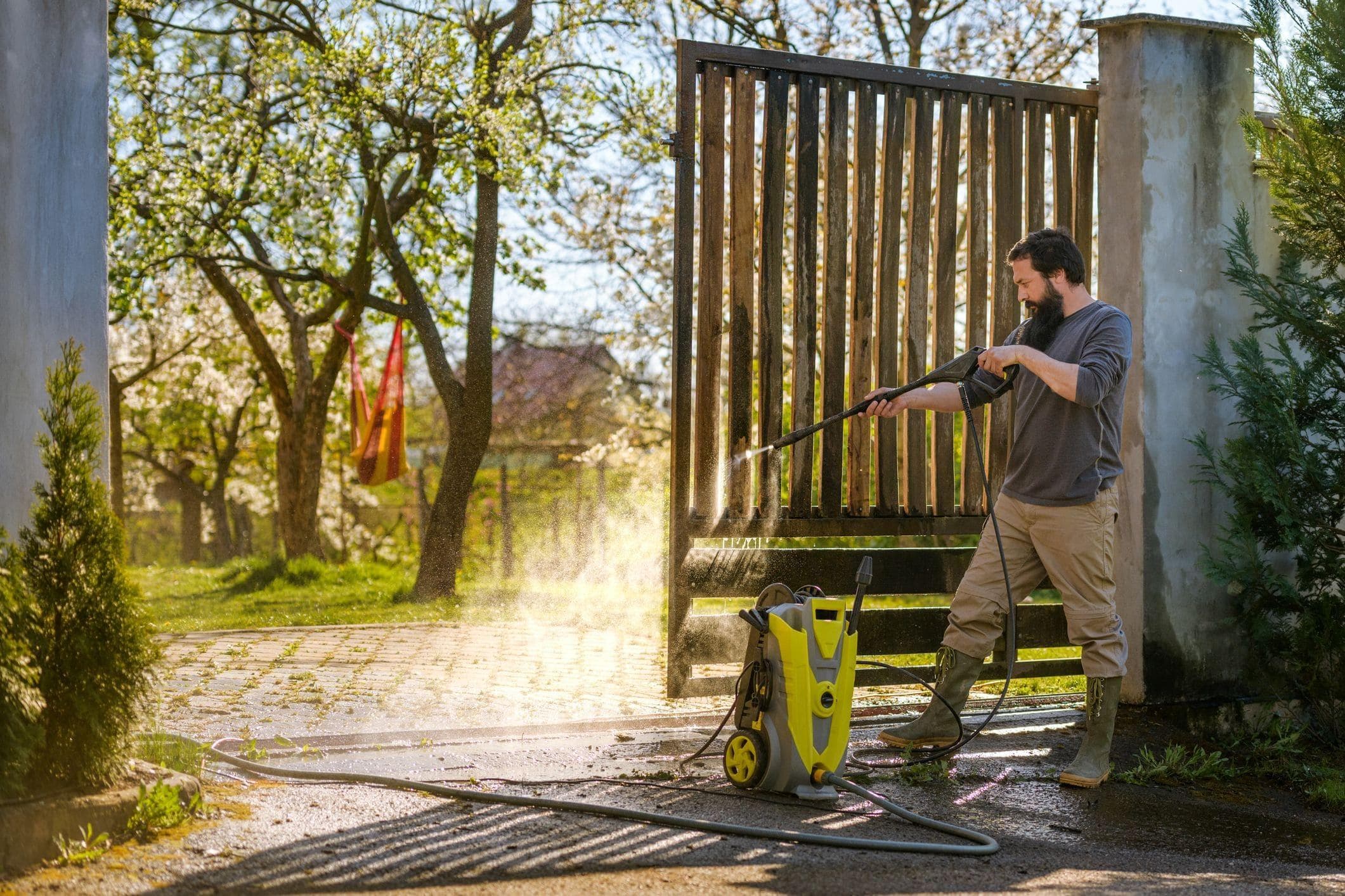 man cleaning swing gate area with powerwasher