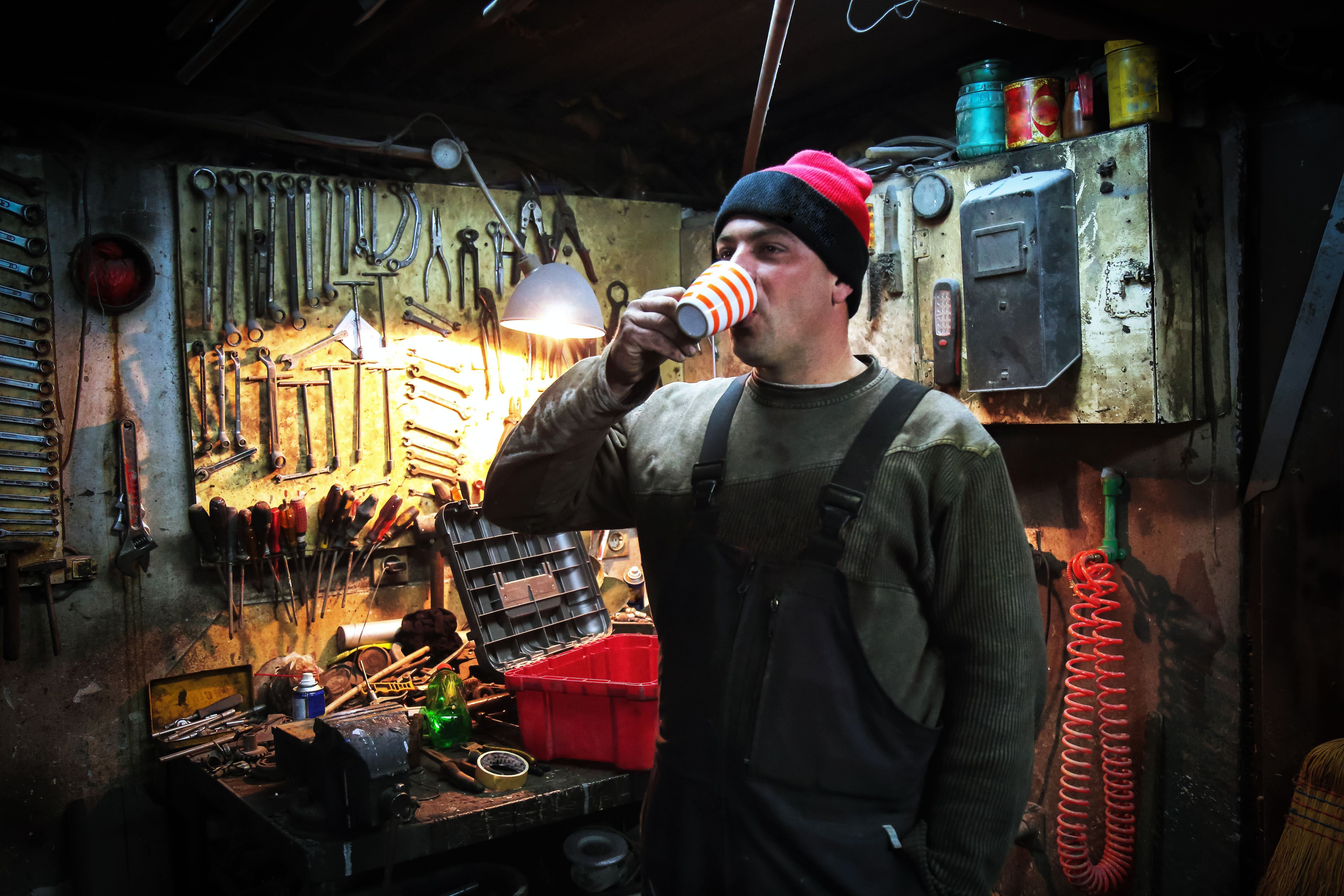 a cold man taking a coffee break in his drafty home garage