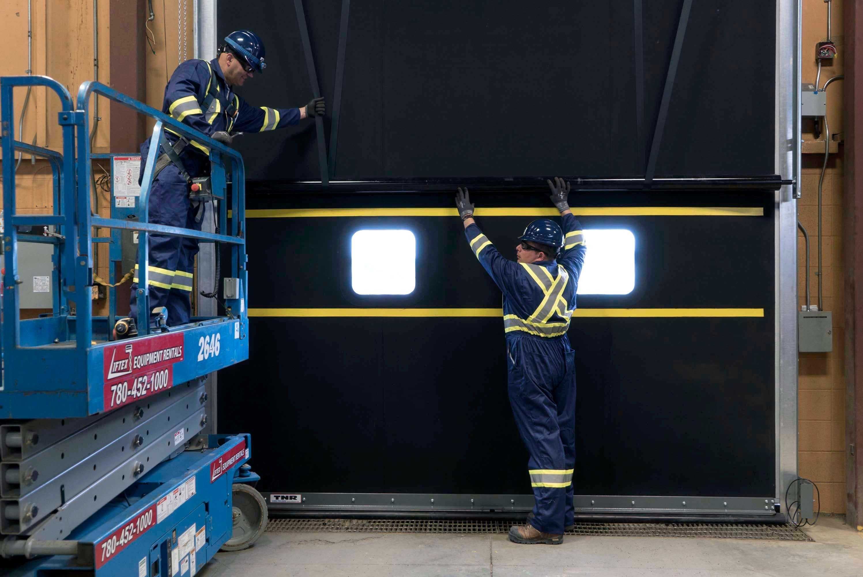 two creative door technicians performing planned maintenance on a large commercial sectional door