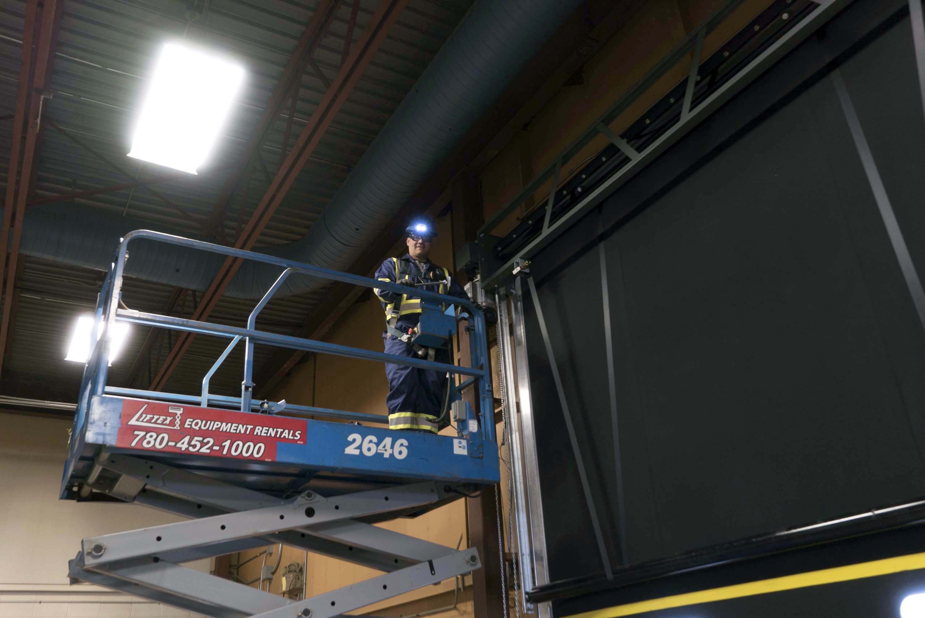 technician on scissor lift servicing a commercial door