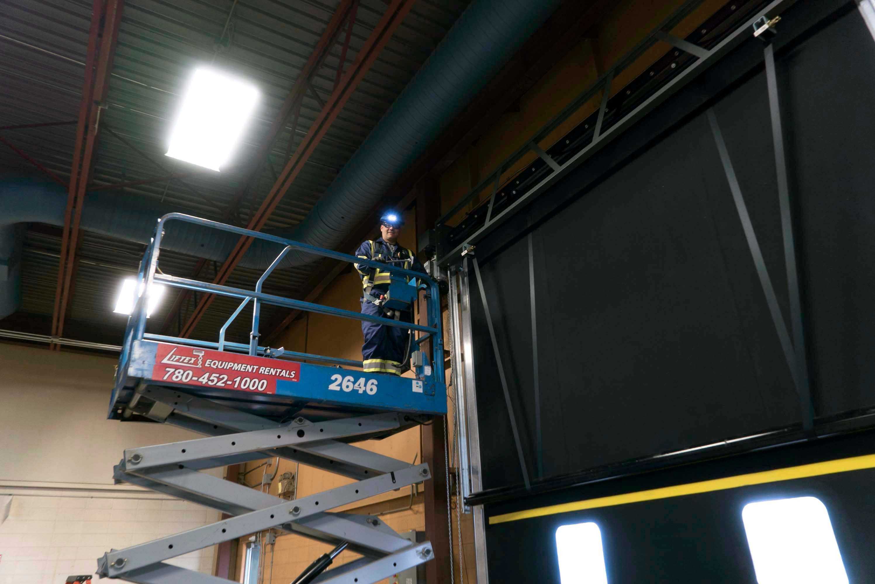 creative door technician in a lift truck inspecting an overhead door creative door technician in a lift truck inspecting an overhead door