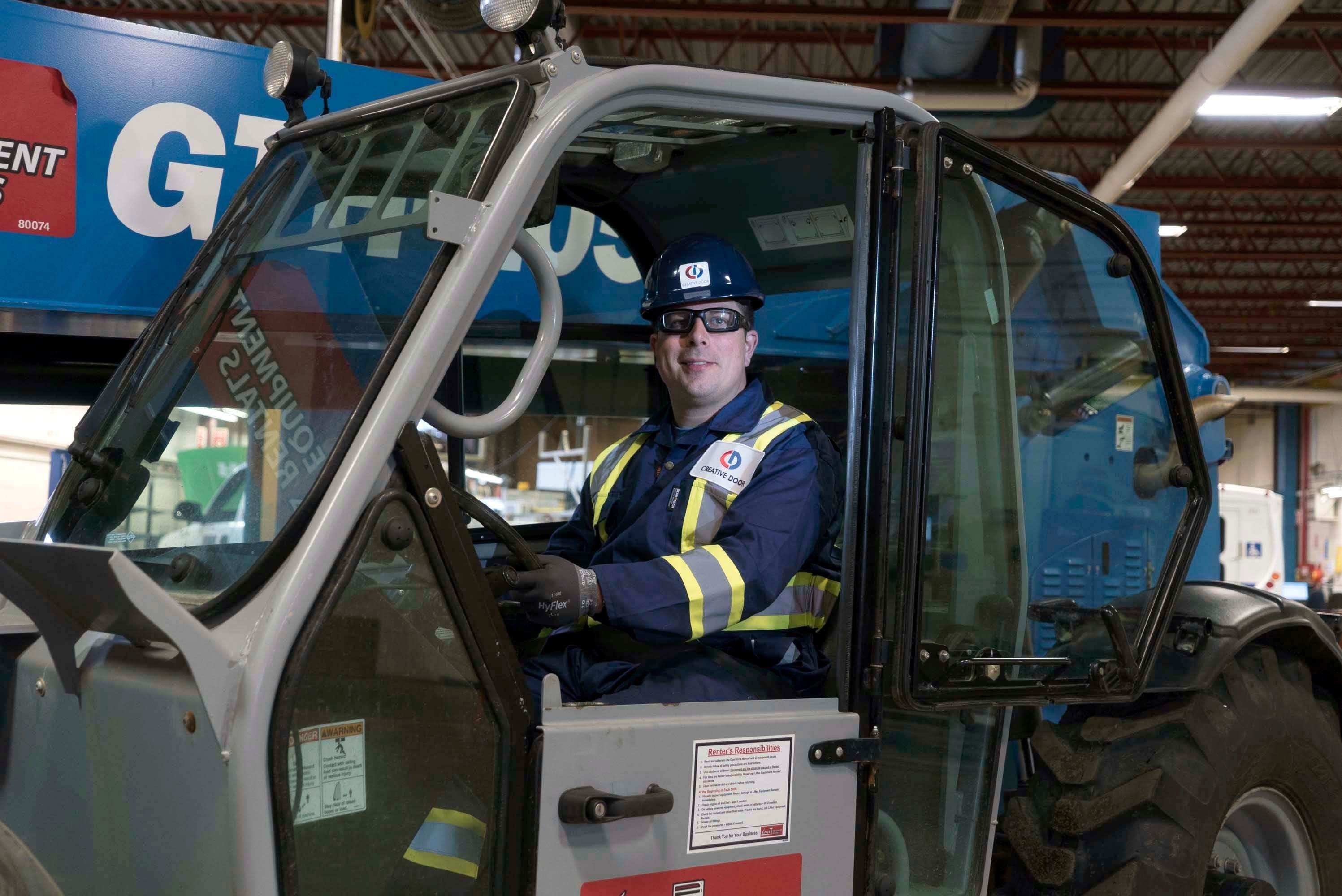 creative door technician smiling in a vehicle inside a warehouse