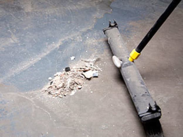 Broom sweeping debris on garage floor