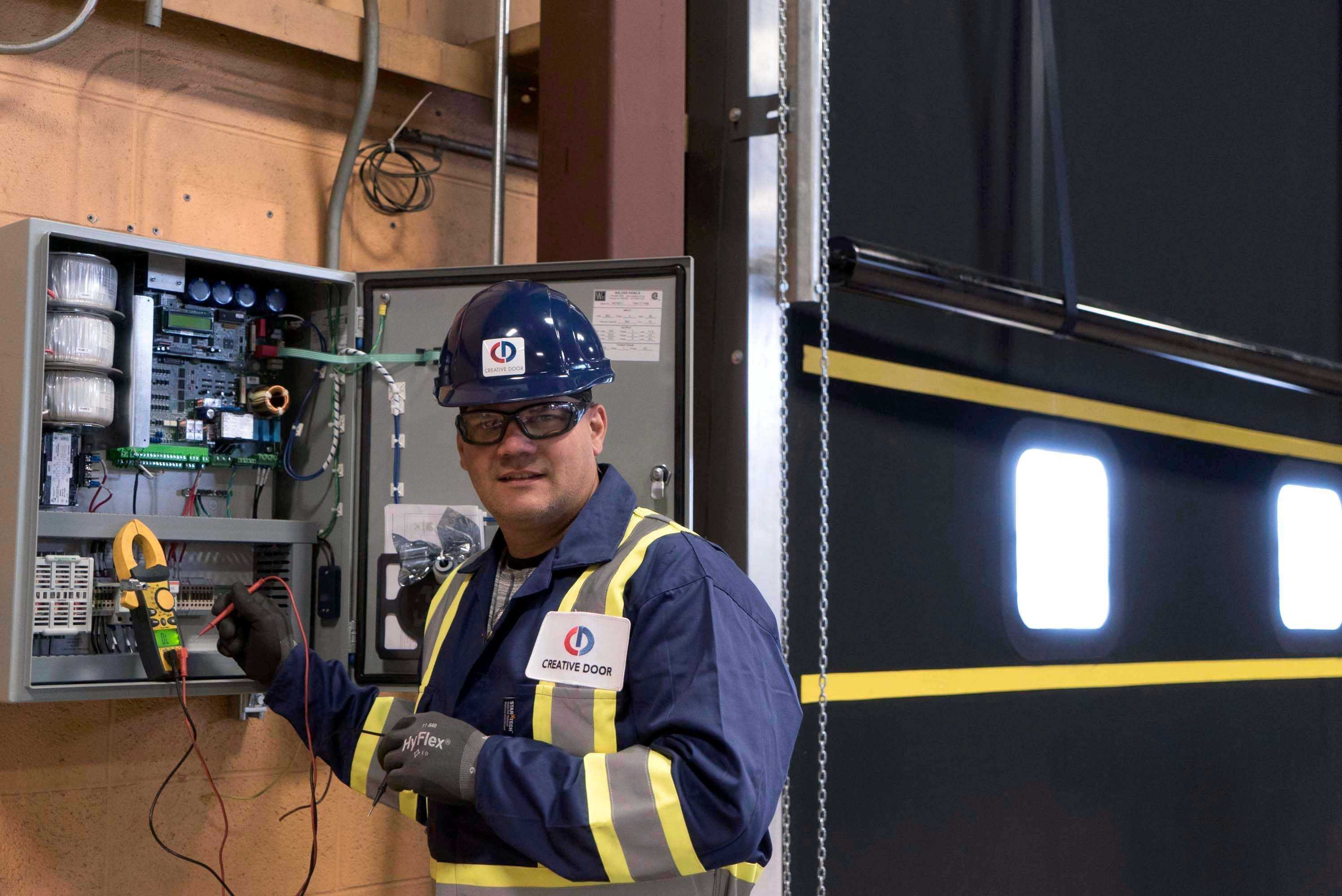 creative door technician working on electrical panel for overhead door operation creative door technician working on electrical panel for overhead door operation