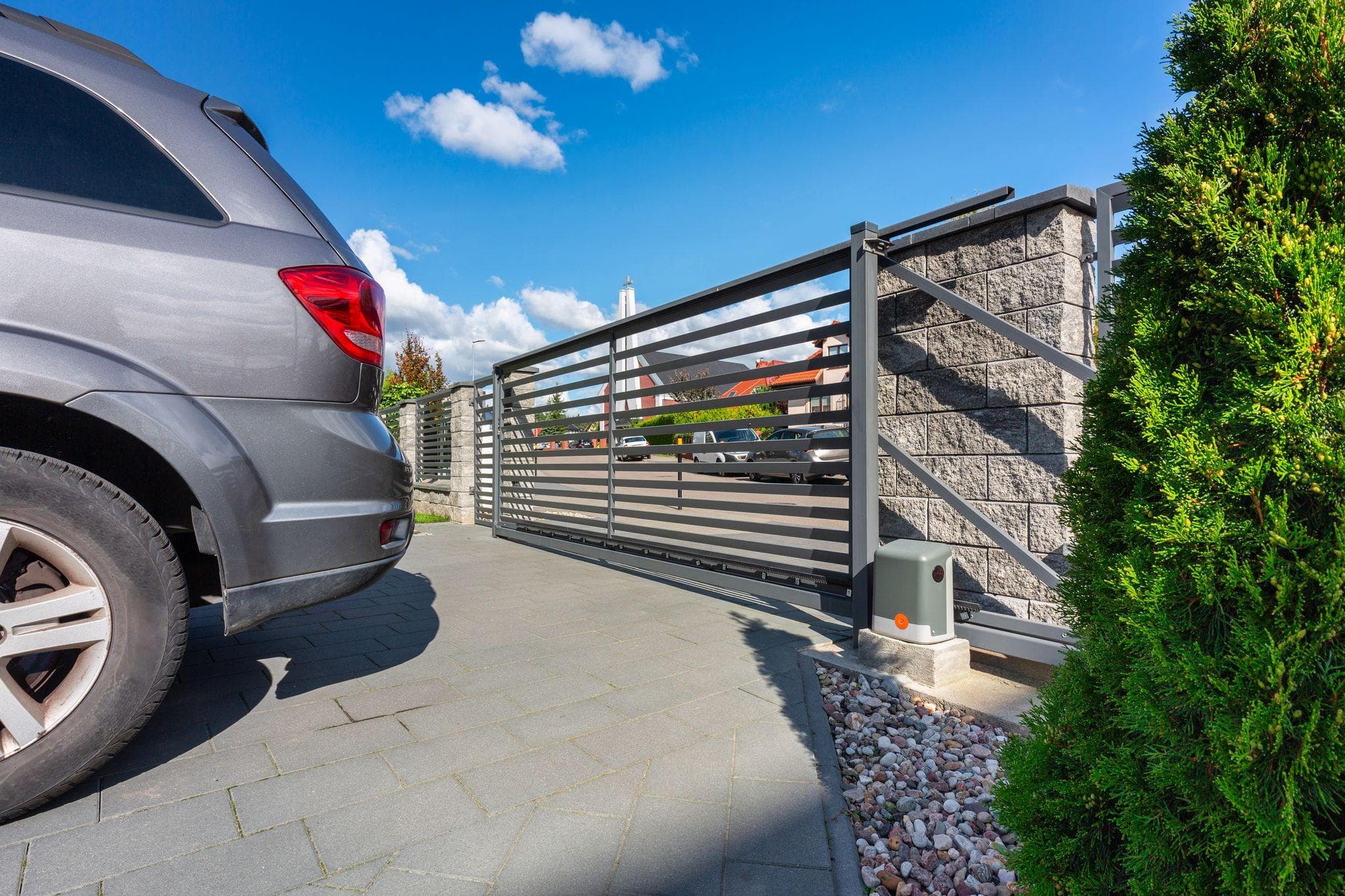 a suburban driveway with car and automatic slide gate