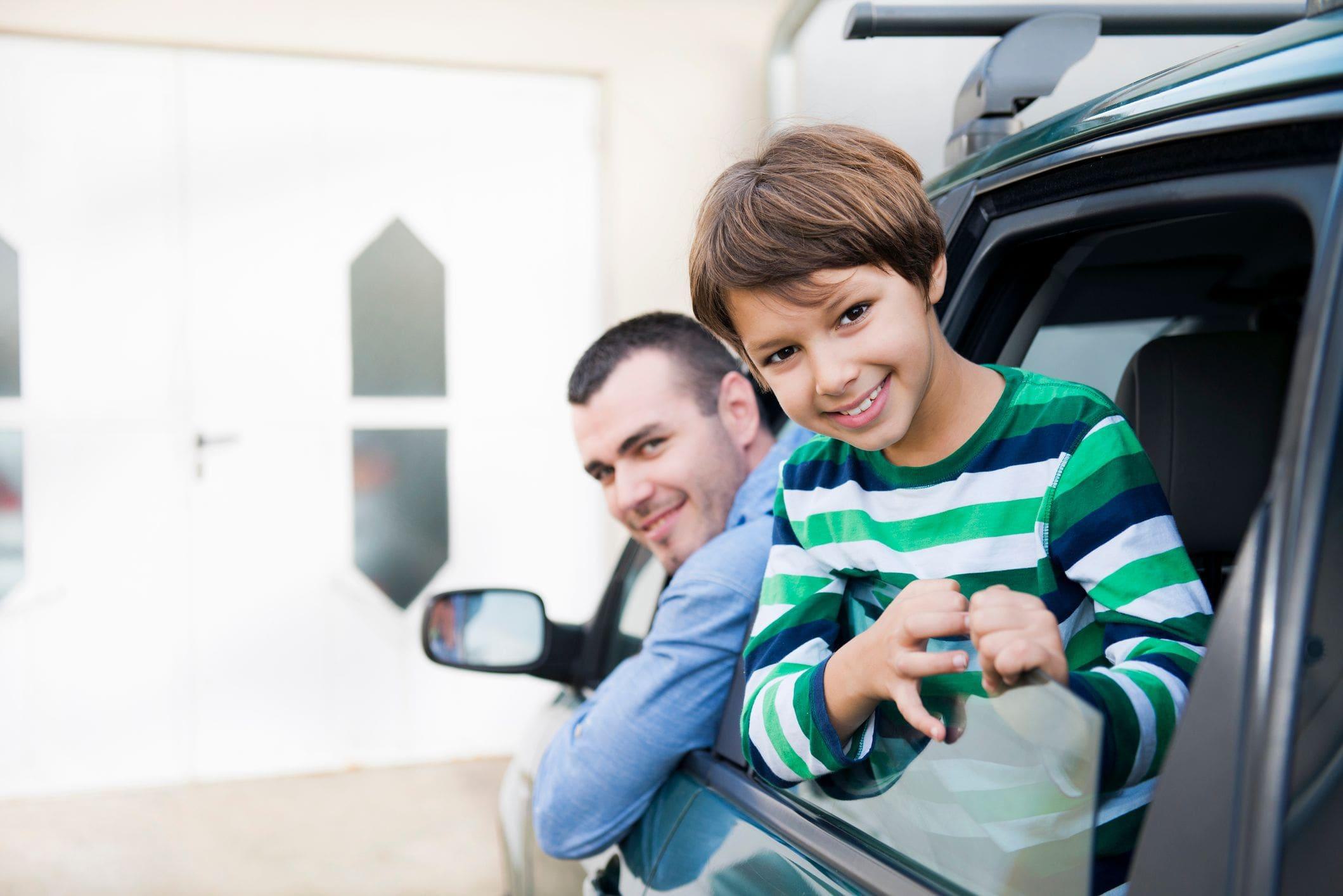 father and son inside car in driveway ready to enter the garage