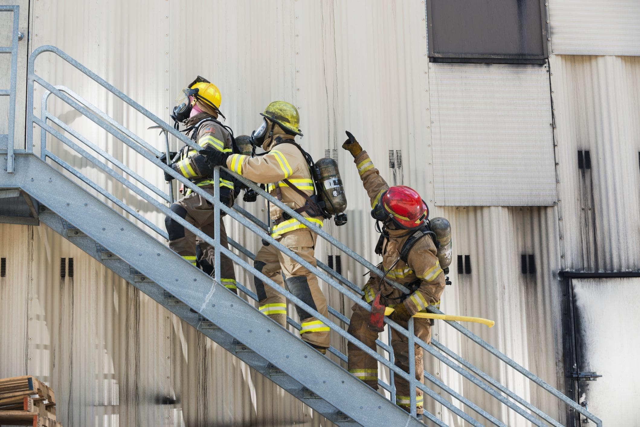 firemen ascending staircase of industrial building
