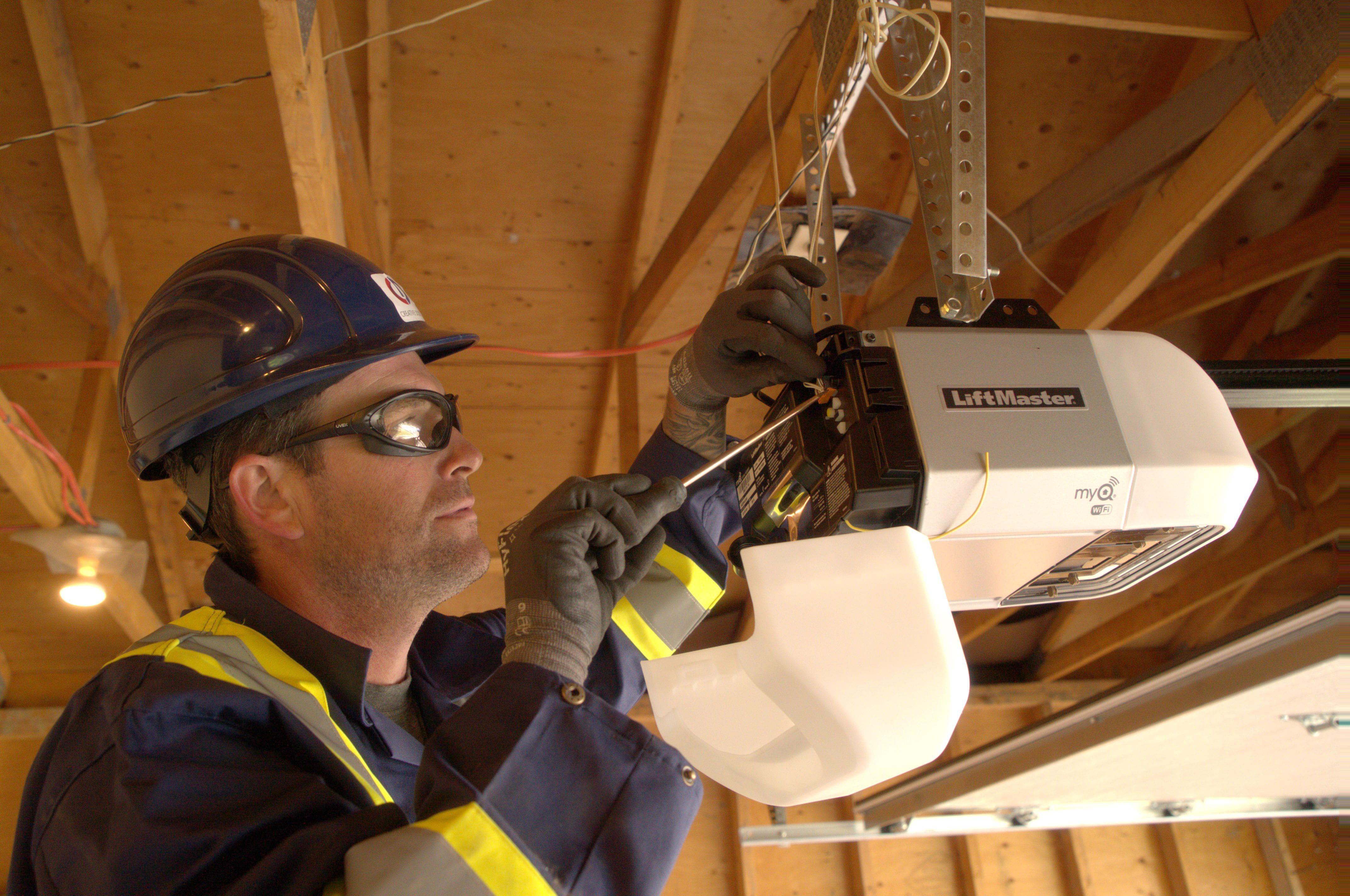 creative door technician performing mechanical maintenance on a garage door operator