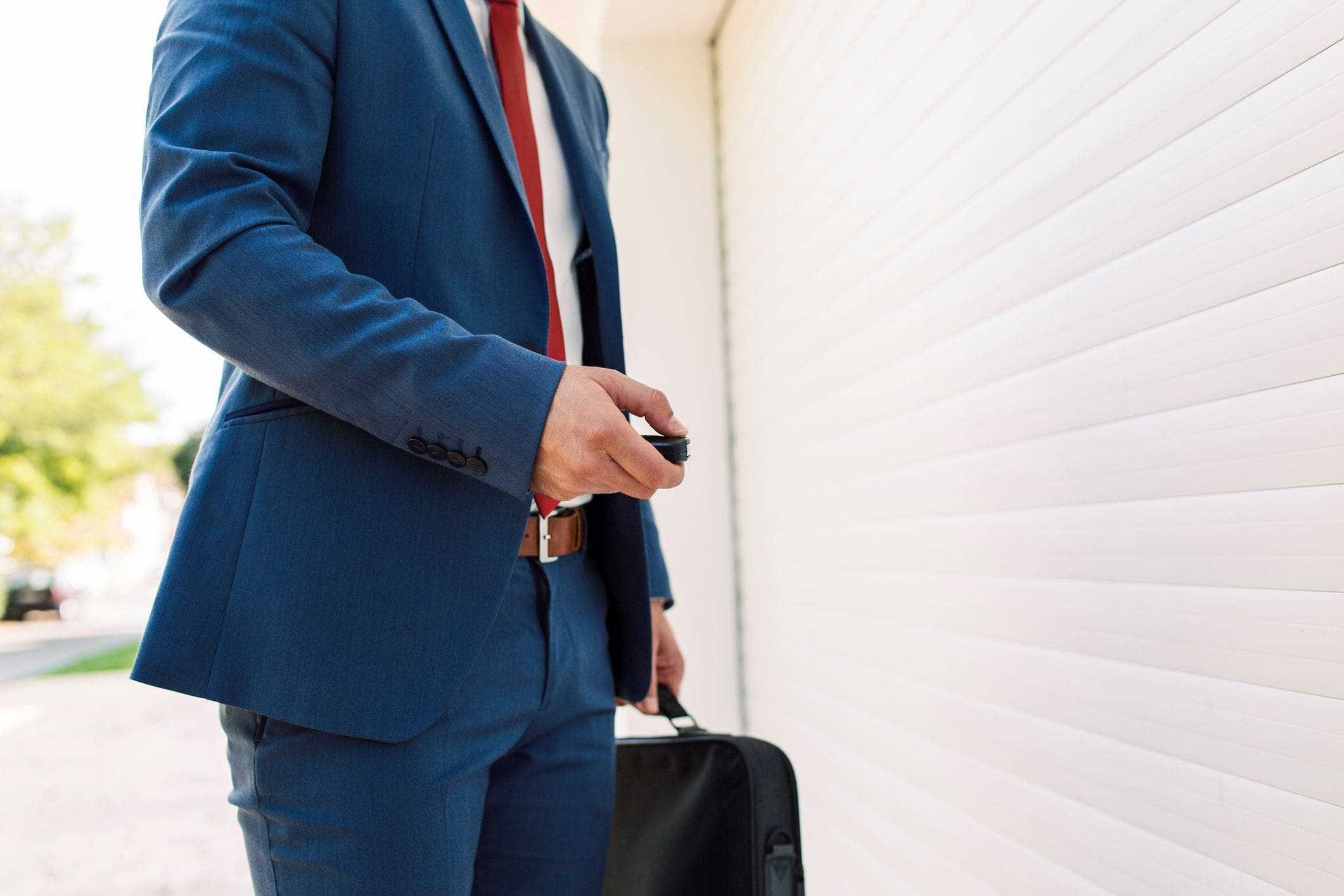man in suit returning home from work opening garage door using remote man in suit returning home from work opening garage door using remote