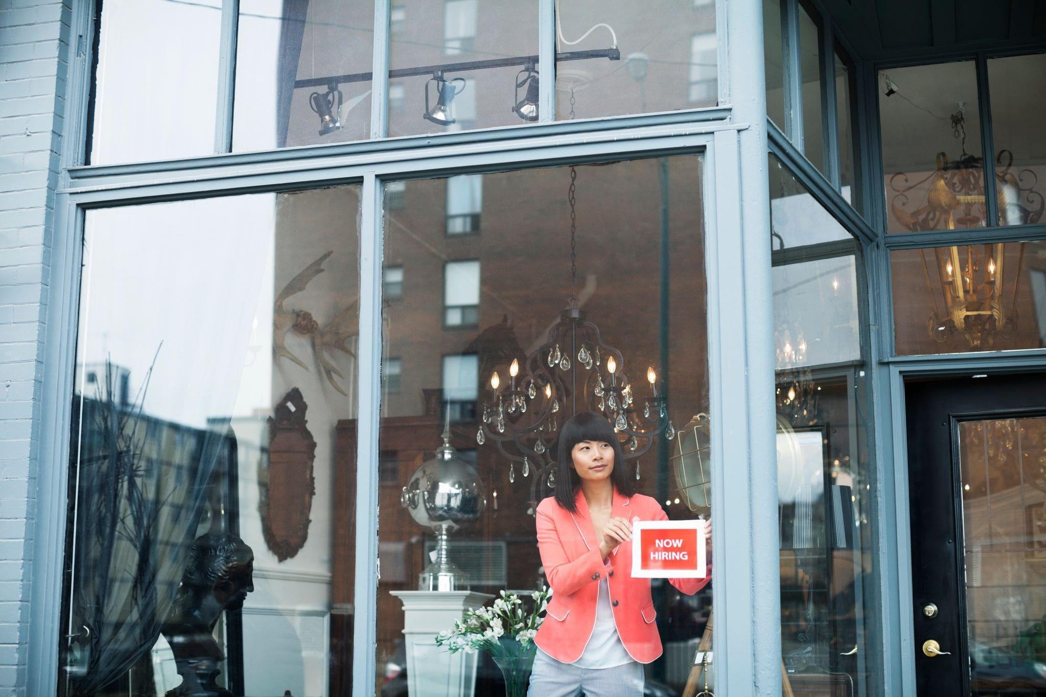 female business owner in window of storefront shop downtown female business owner in window of storefront shop downtown