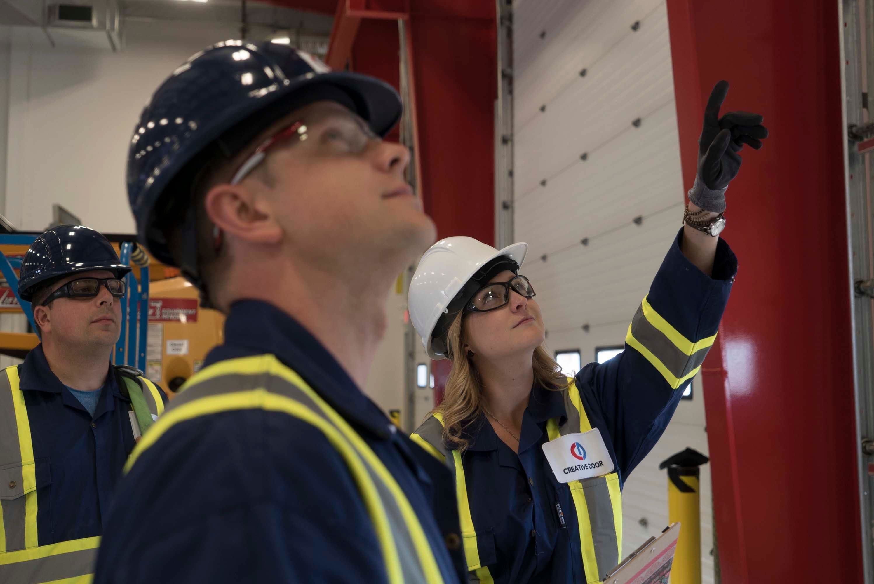 a group of commercial technicians from Creative Door Services inspecting a large overhead commercial door